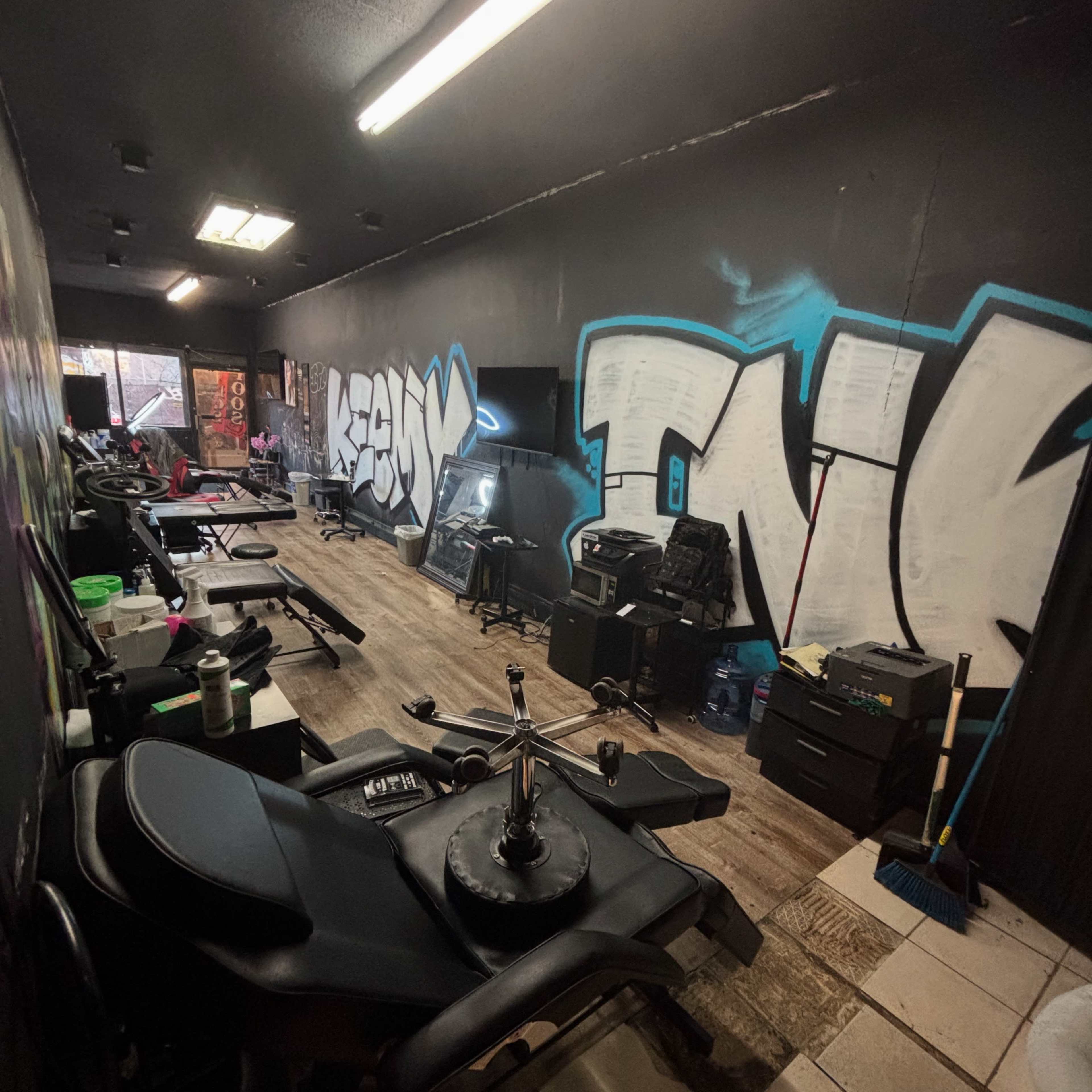 The image shows a gym interior with various exercise equipment lined up against the walls, accented by graffiti-style art on the dark walls.