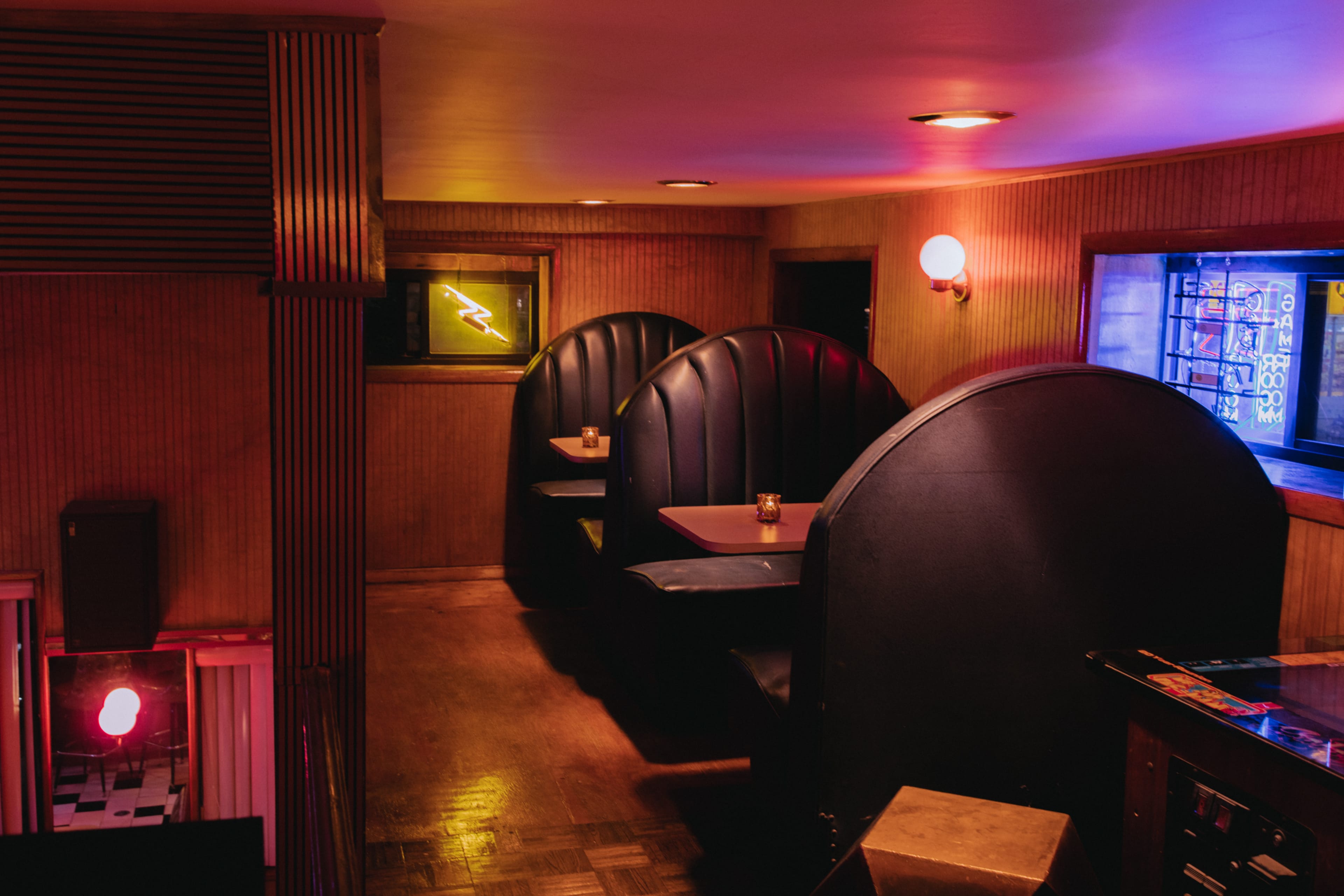 The image shows a dimly lit retro diner interior with vinyl booth seating and neon signage.