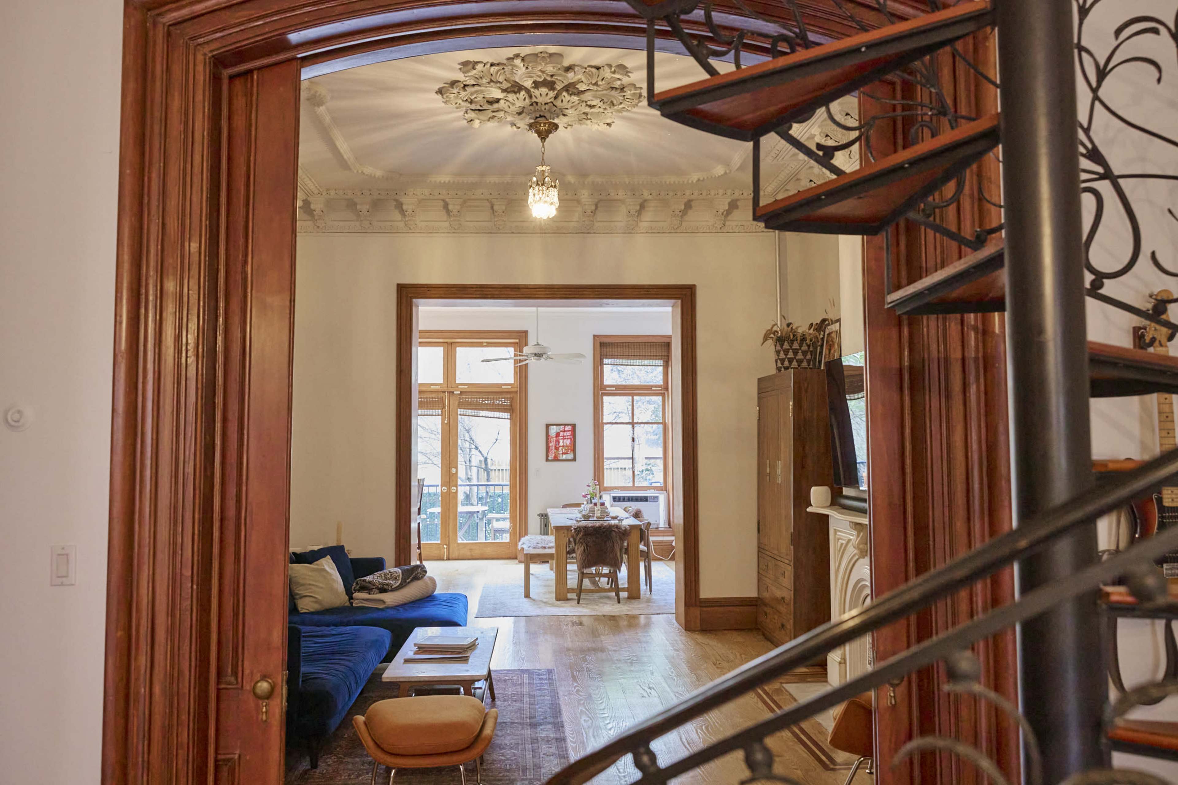 A staircase leading to a living room with large windows and a dining area in the background.
