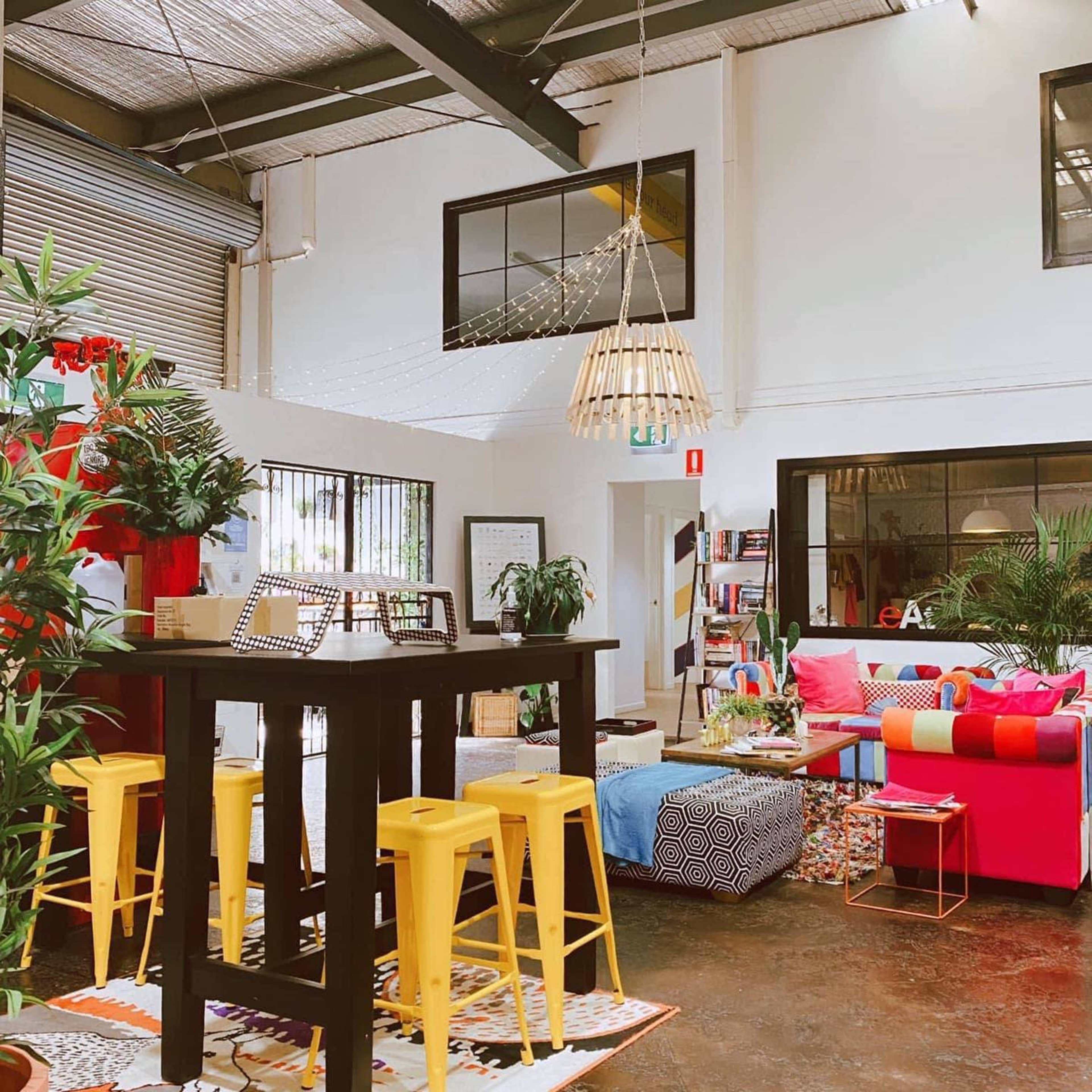 A vibrant indoor space features a mix of colorful furniture, plants, and decorative lighting.