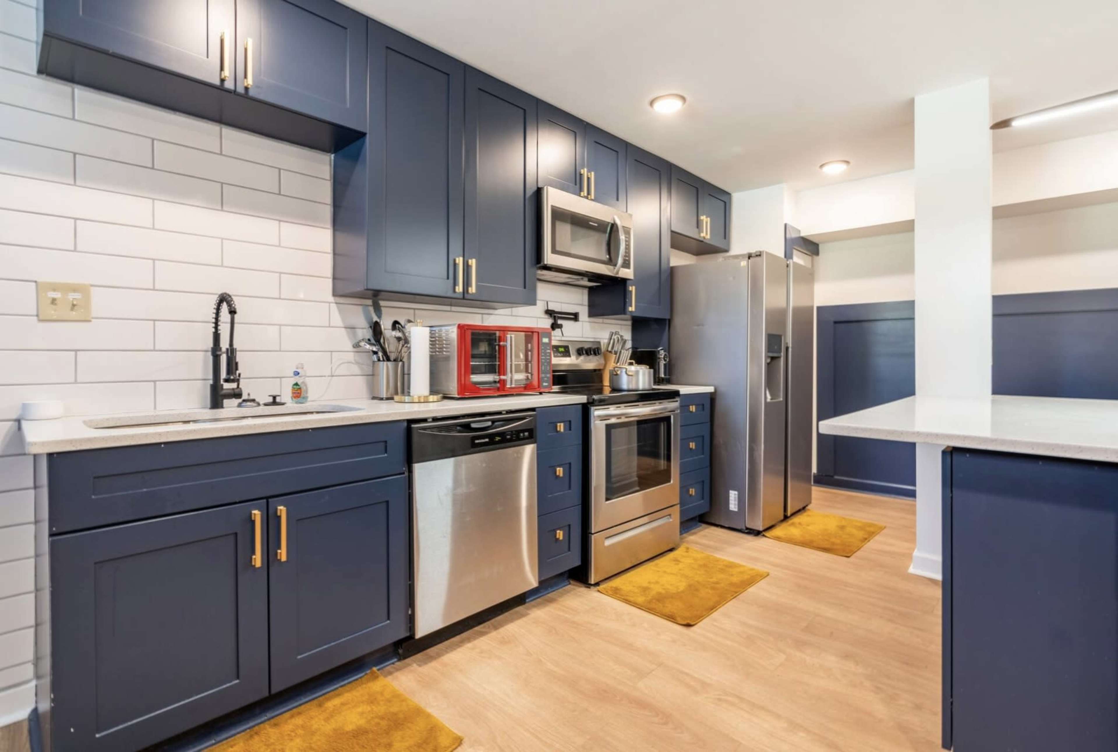 A modern kitchen features navy blue cabinetry, stainless steel appliances, and a combination of countertop and open shelving.