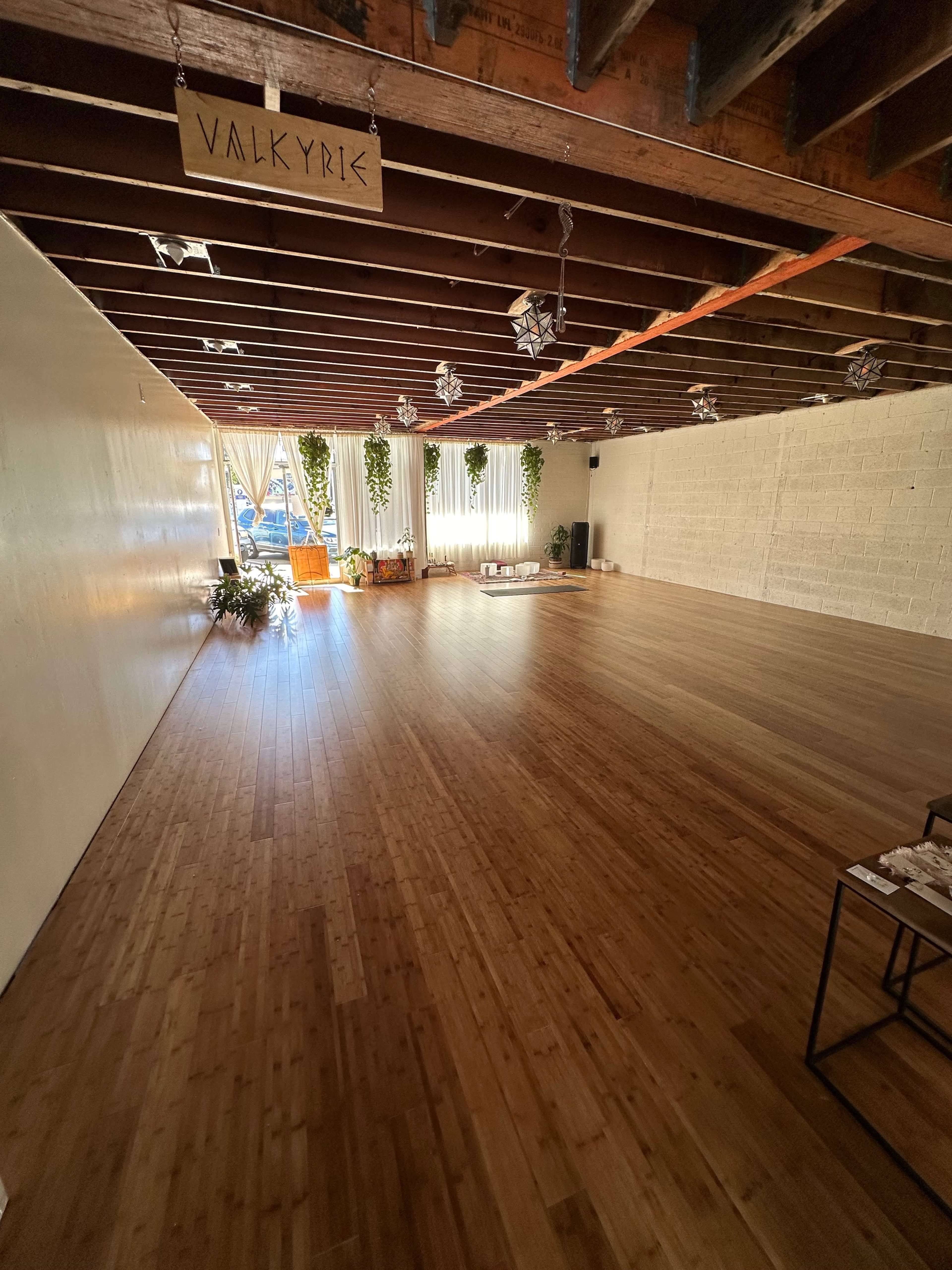 A spacious interior with bamboo flooring, large windows allowing natural light, and plants lining the walls in a minimalist environment labeled "VALKYRIE."