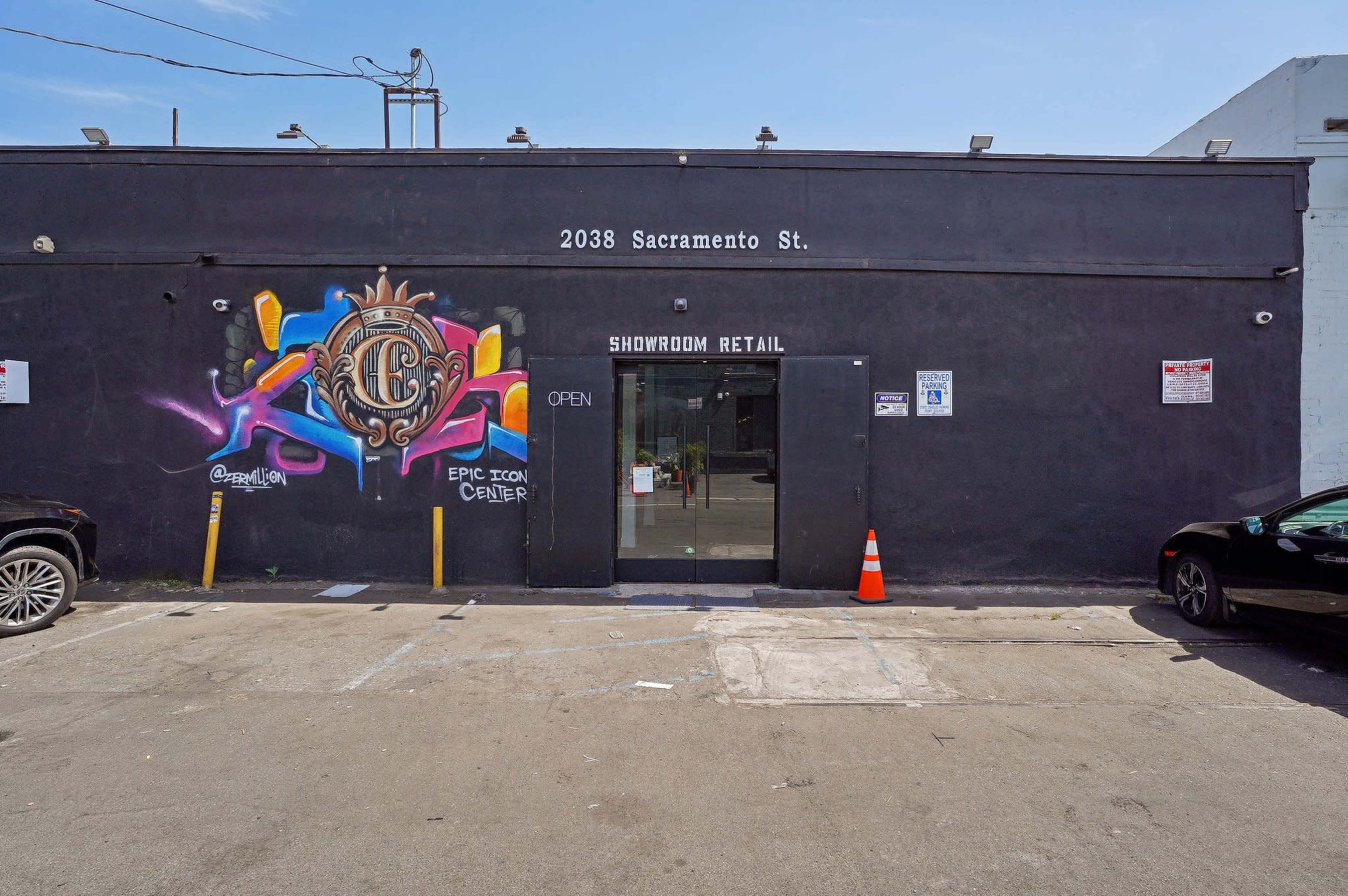 The image shows a black building facade with a colorful mural on the left side, featuring the text "2038 Sacramento St." above the entrance labeled "SHOWROOM RETAIL."