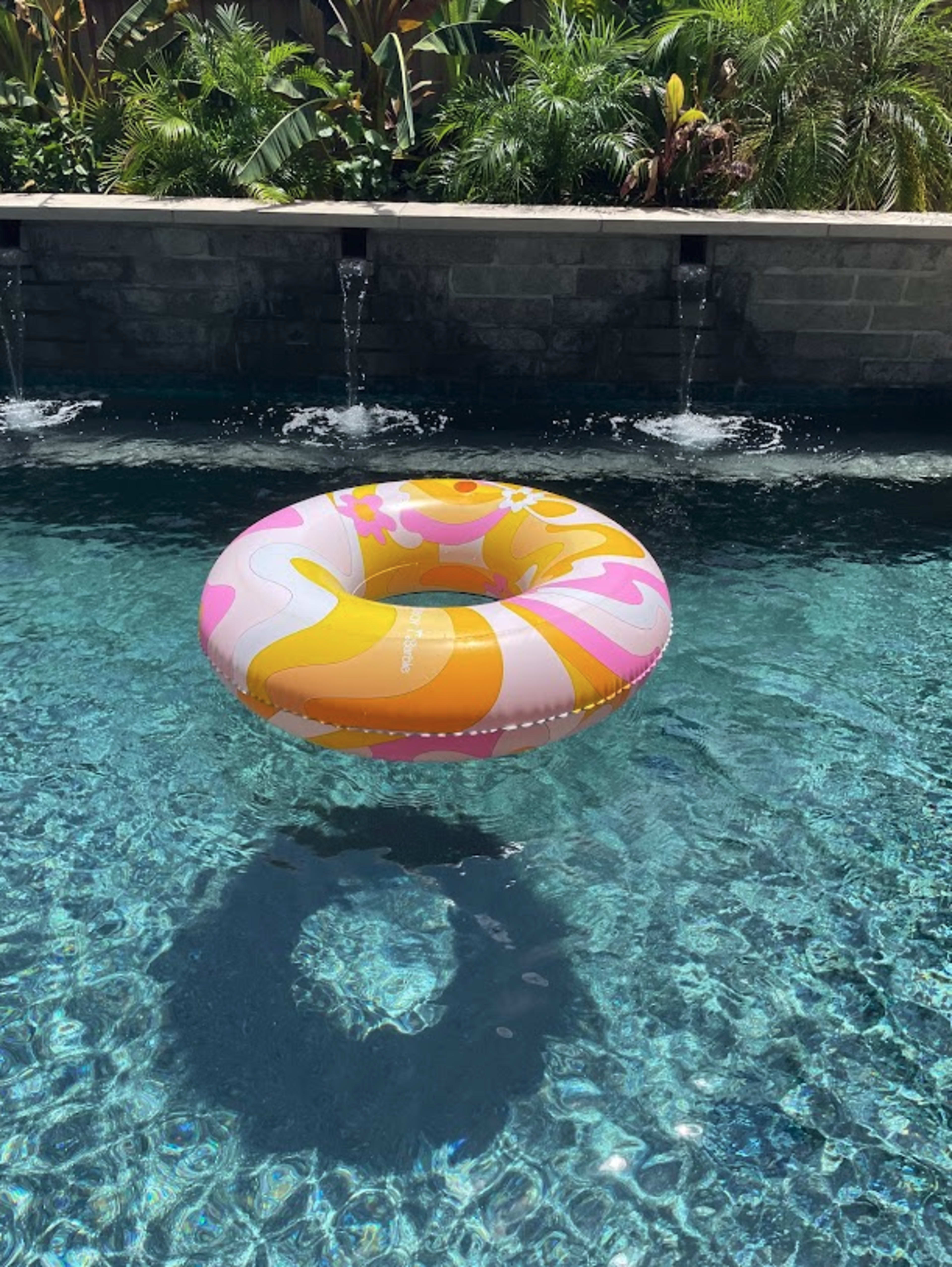 A colorful inflatable ring floats on the surface of a clear blue swimming pool.