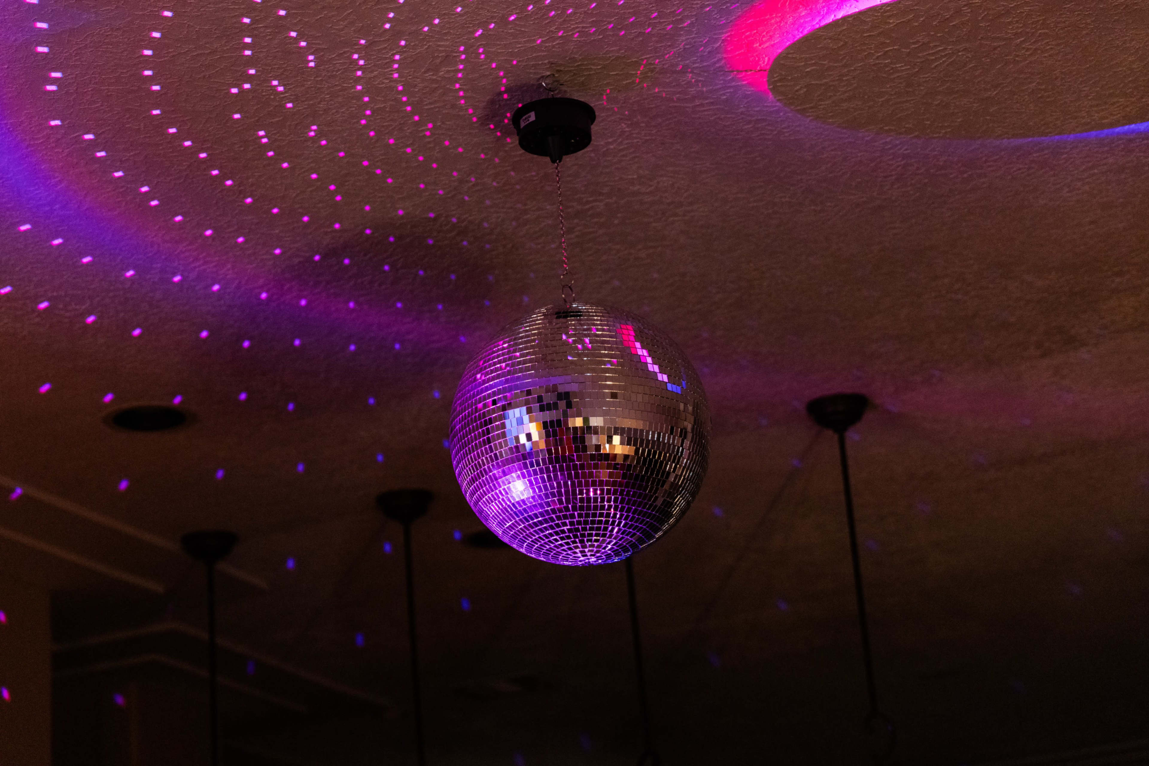 A disco ball hangs from the ceiling, reflecting colorful lights onto the surrounding surface.