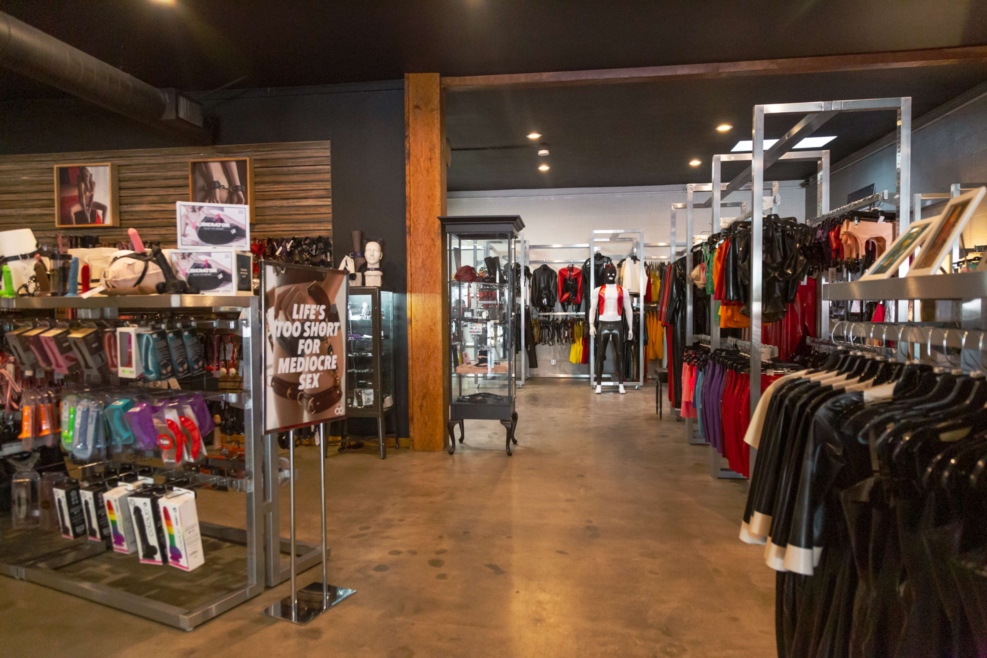 The interior of a retail store with clothing and adult products on display, featuring racks of garments and shelves with various items.