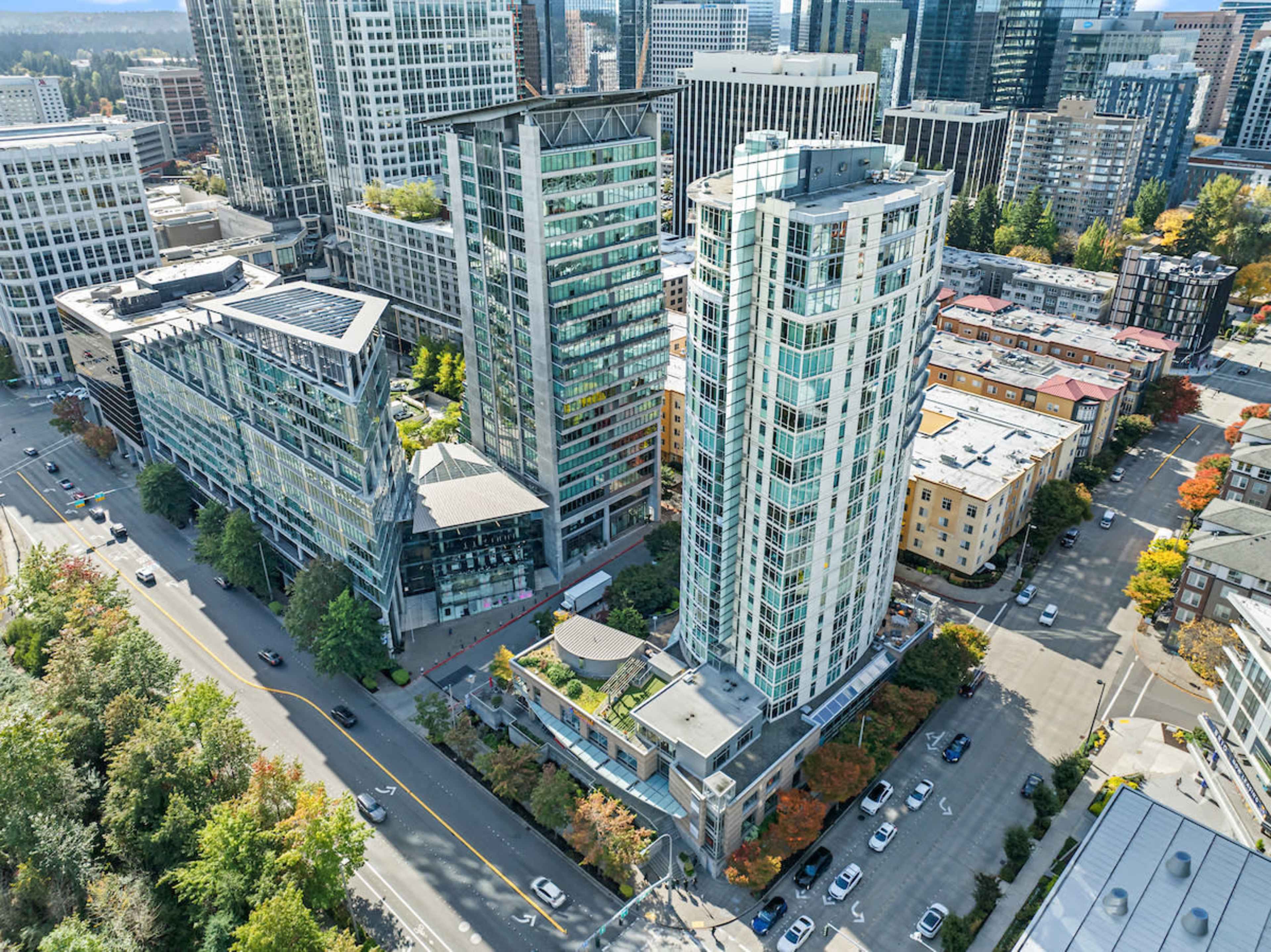 The image shows an aerial view of a modern urban landscape featuring high-rise buildings, street-lined sections, and a mix of commercial and residential architecture.