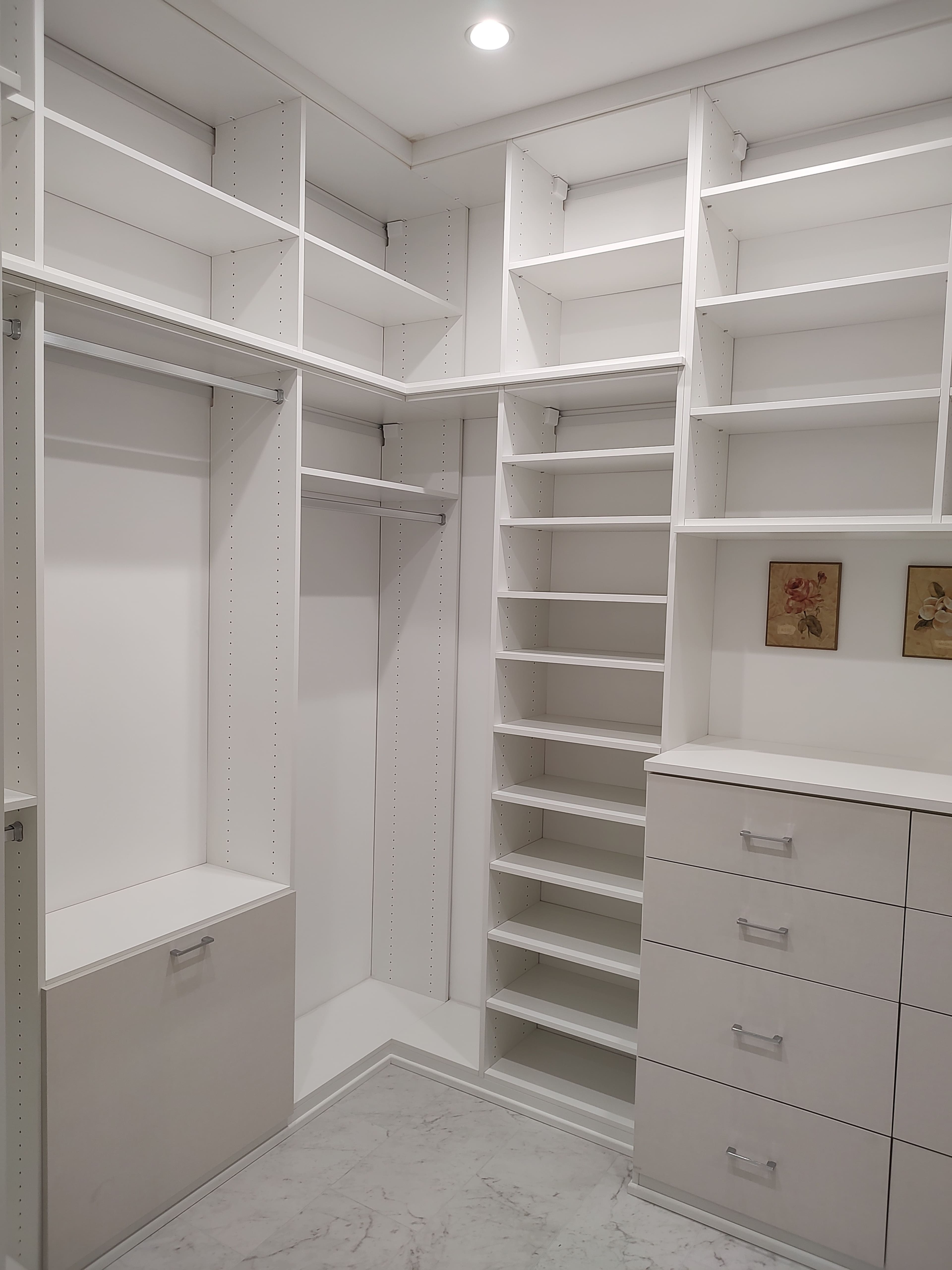 A spacious white closet with open shelving, a hanging rod, and a set of drawers.