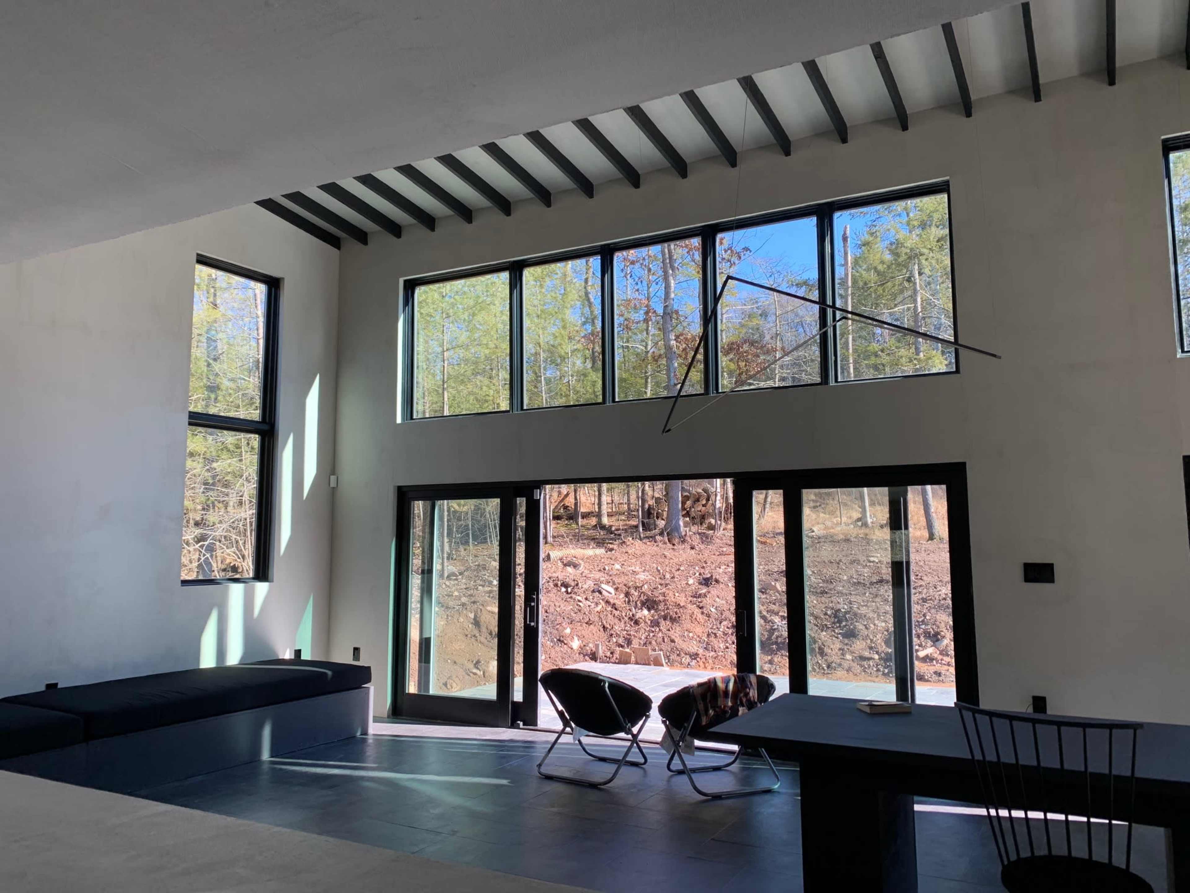 A modern interior space with large windows overlooking a wooded area.