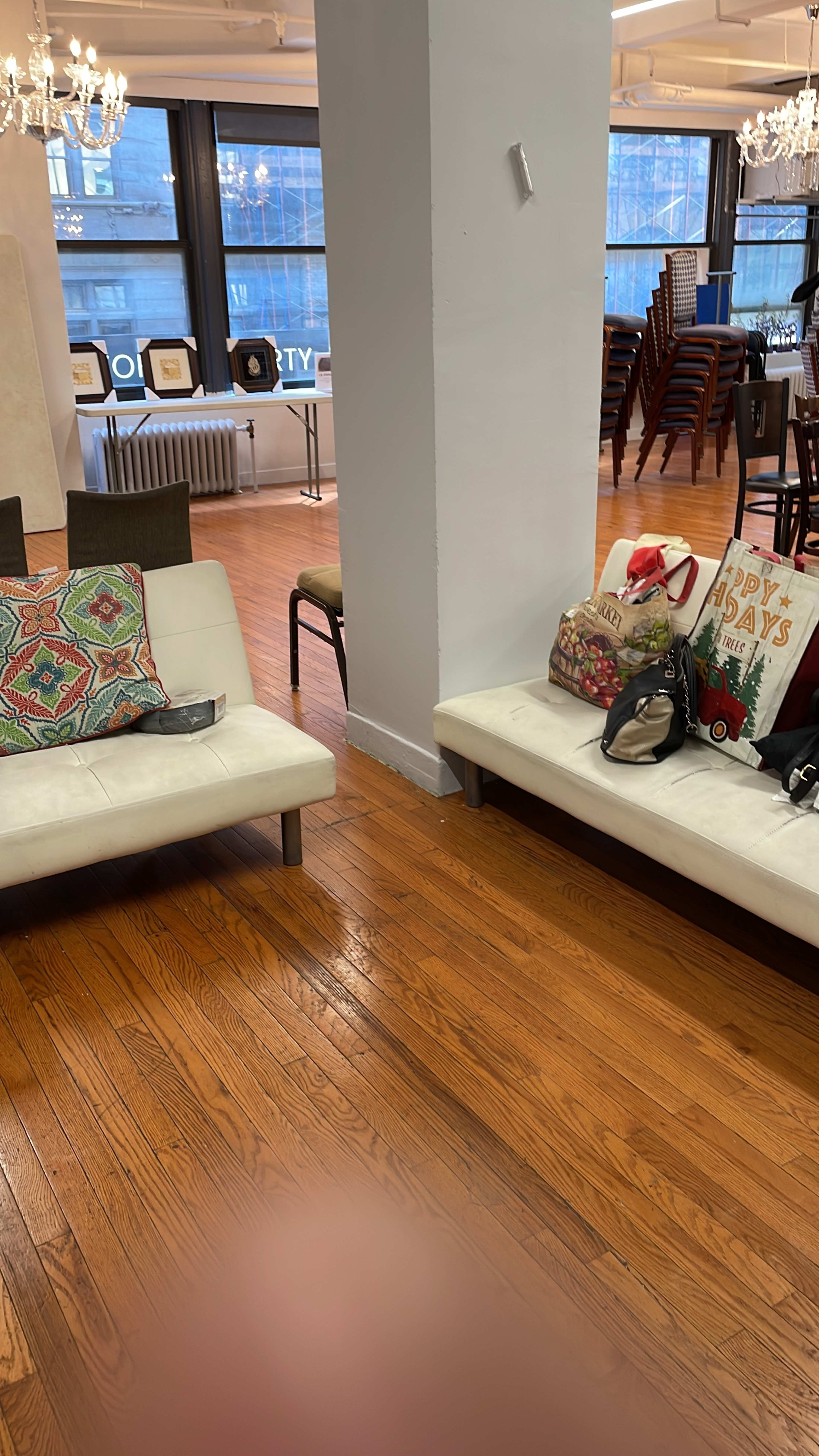A spacious interior with white benches and various chairs, featuring decorative pillows and bags on the floor.