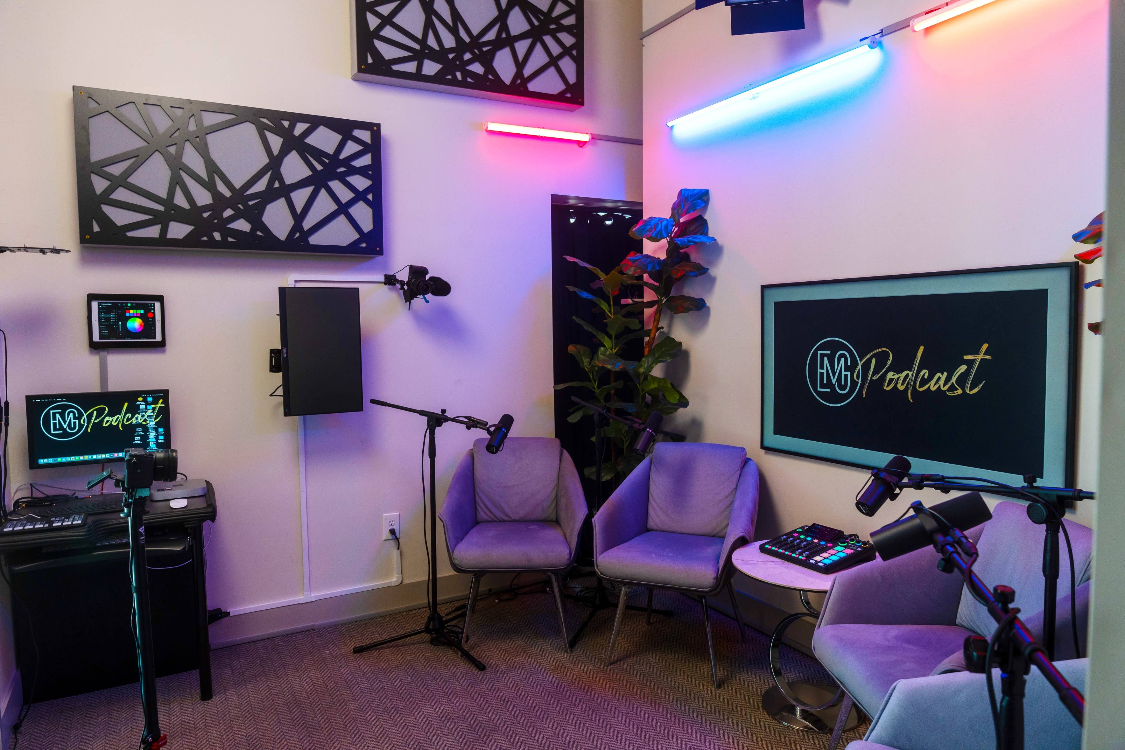 The image shows a modern podcast recording studio with gray chairs, colorful neon lights, and equipment for audio production.