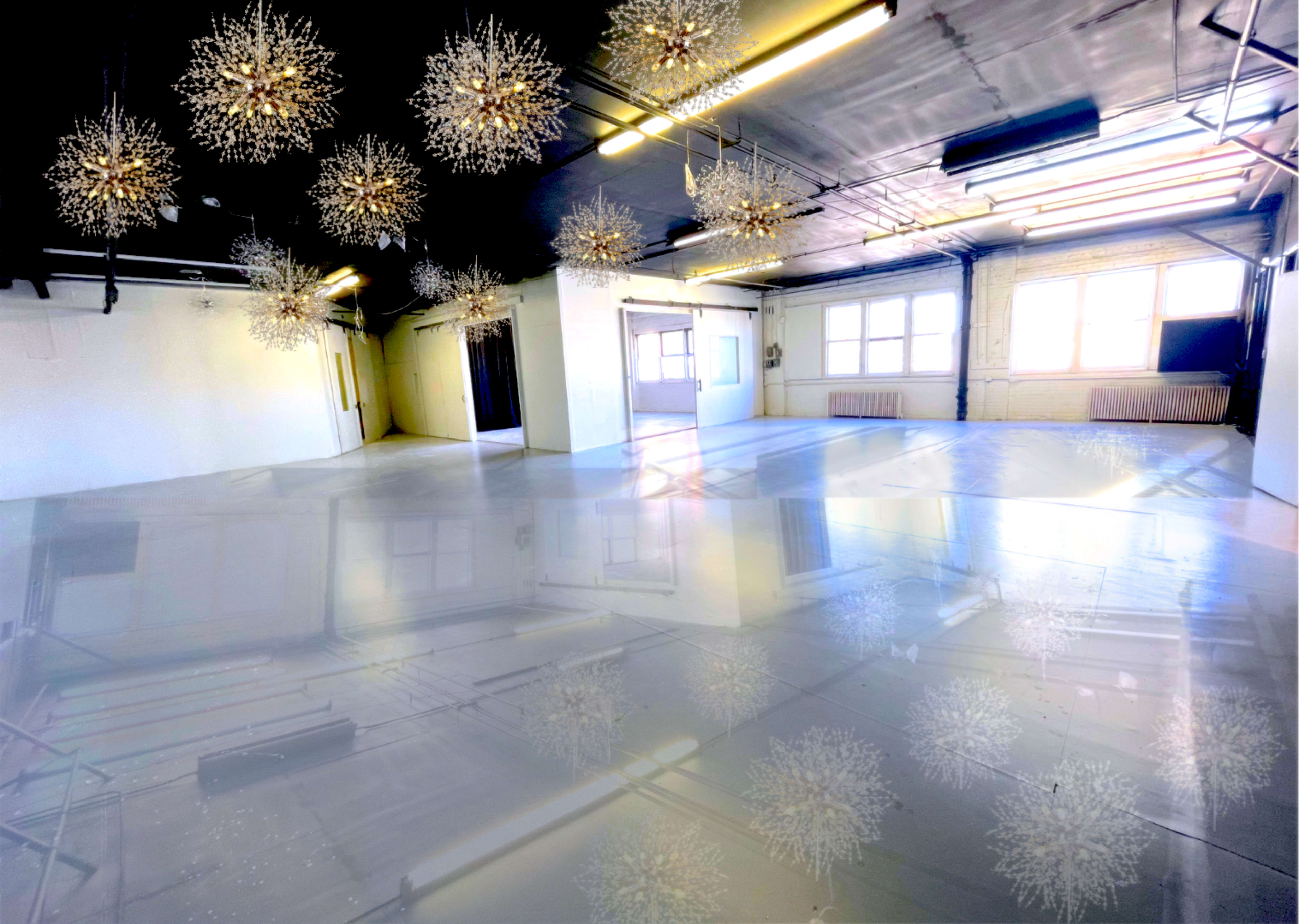 The image shows a spacious, empty room with polished floors and decorative hanging light fixtures.