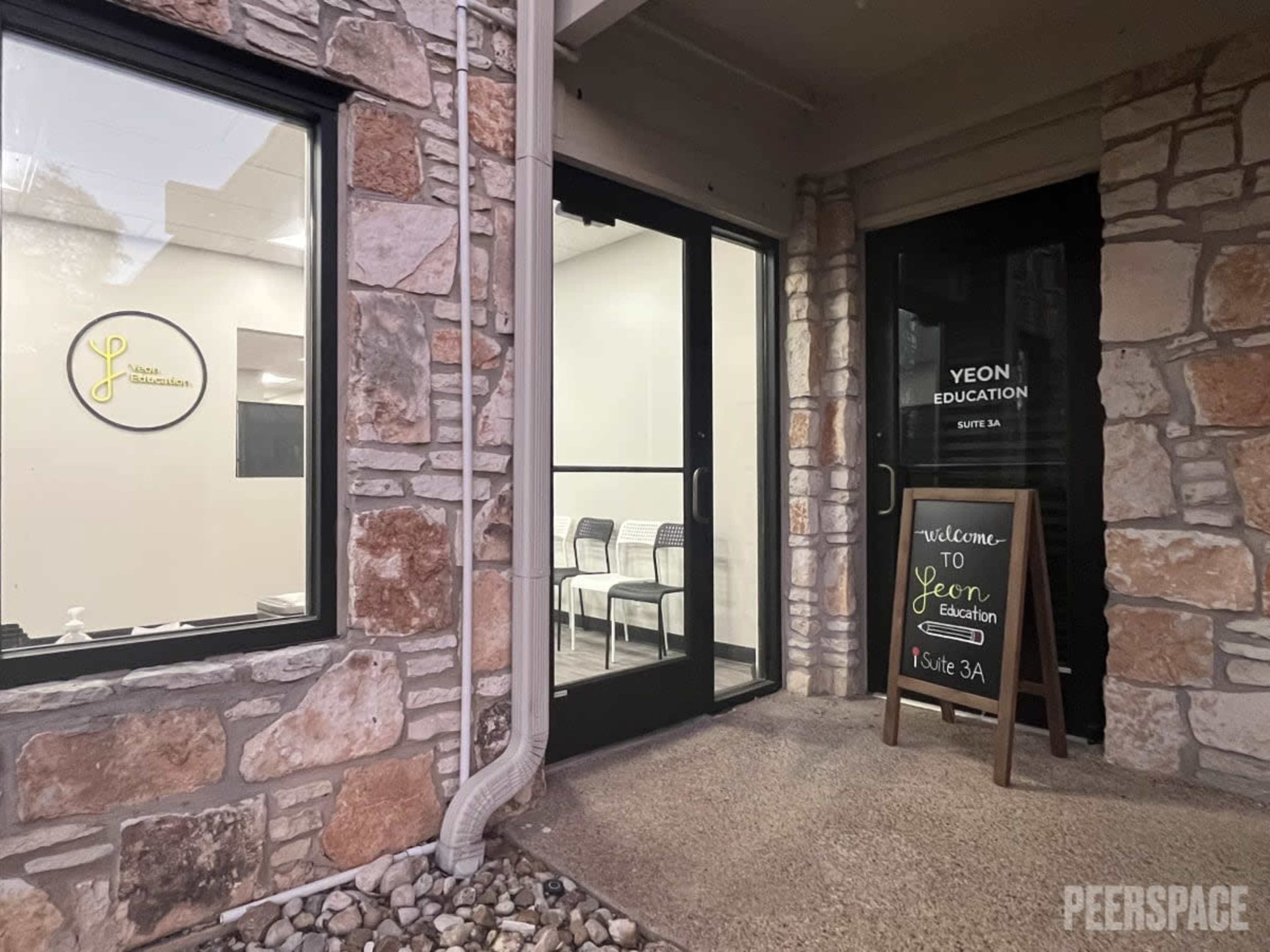 The entrance to Yeon Education features a small sign welcoming visitors and has a waiting area with chairs visible through the front door.