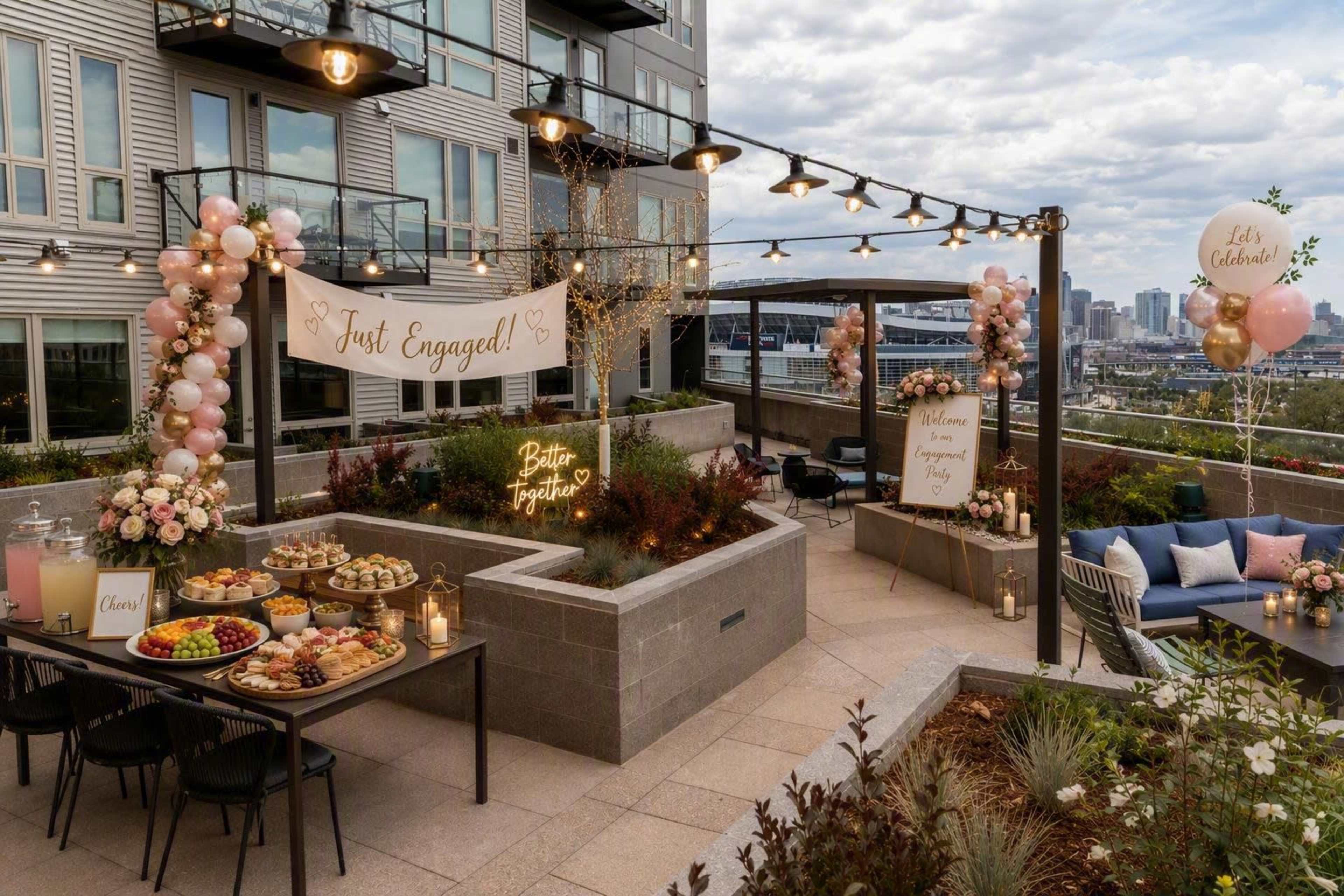 The image shows a decorated outdoor rooftop area featuring a table with assorted desserts, floral arrangements, and banners celebrating an engagement.