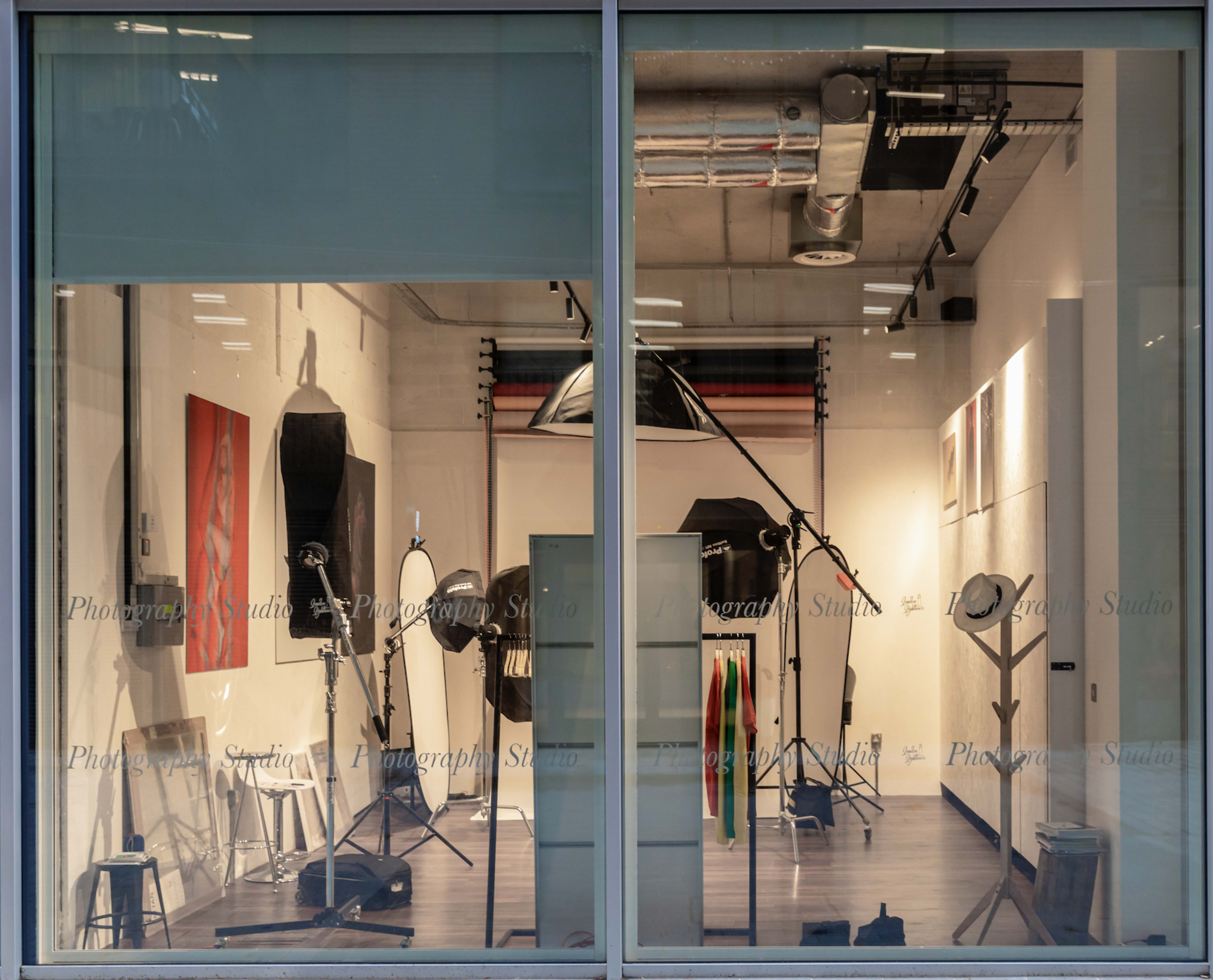 The interior of a photography studio, featuring various lighting equipment and backdrops arranged systematically.