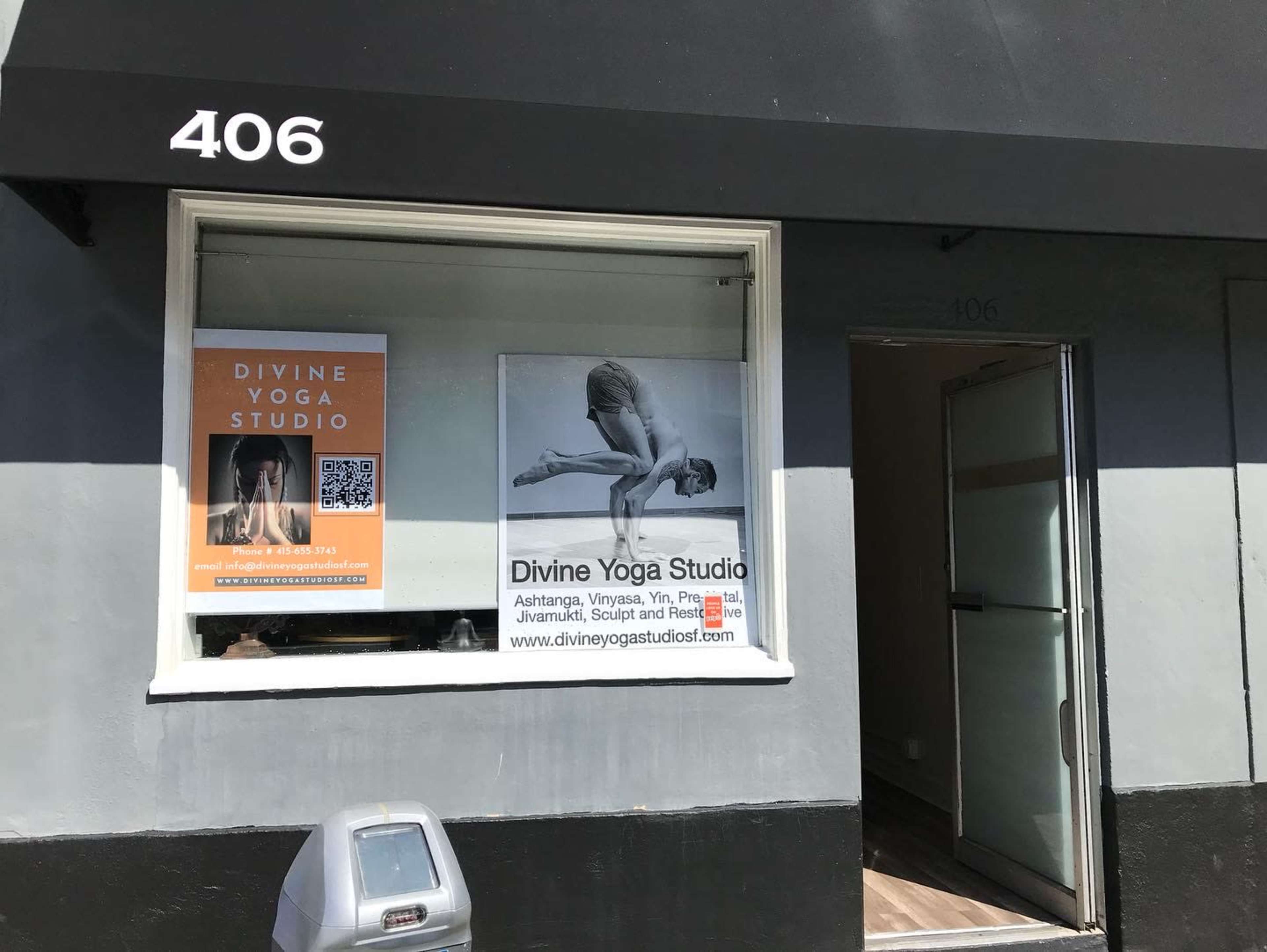 The exterior of a yoga studio with a large window display featuring promotional posters for "Divine Yoga Studio" at the address 406.