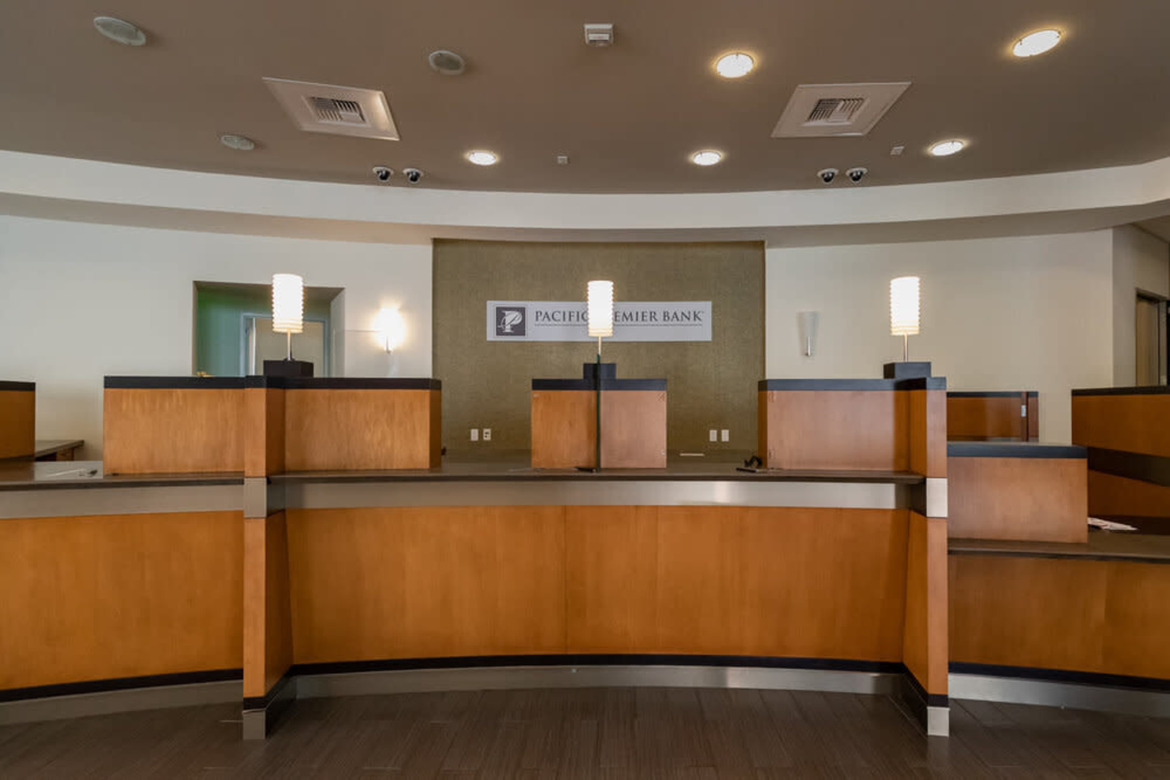 A bank reception area with wooden counters and modern light fixtures.