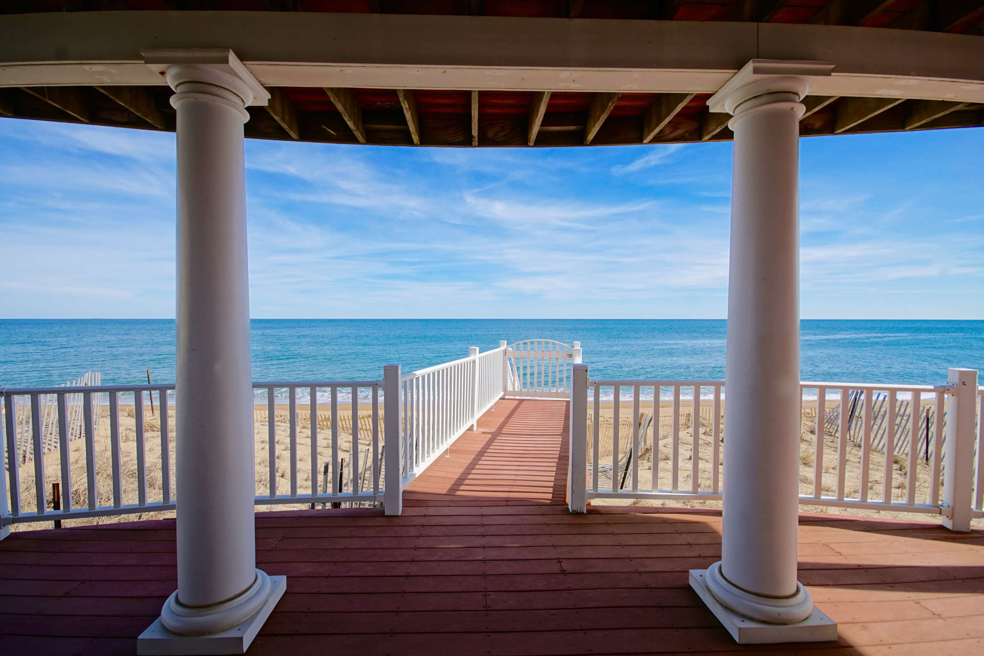 A view of the ocean from a shaded deck framed by two white columns.