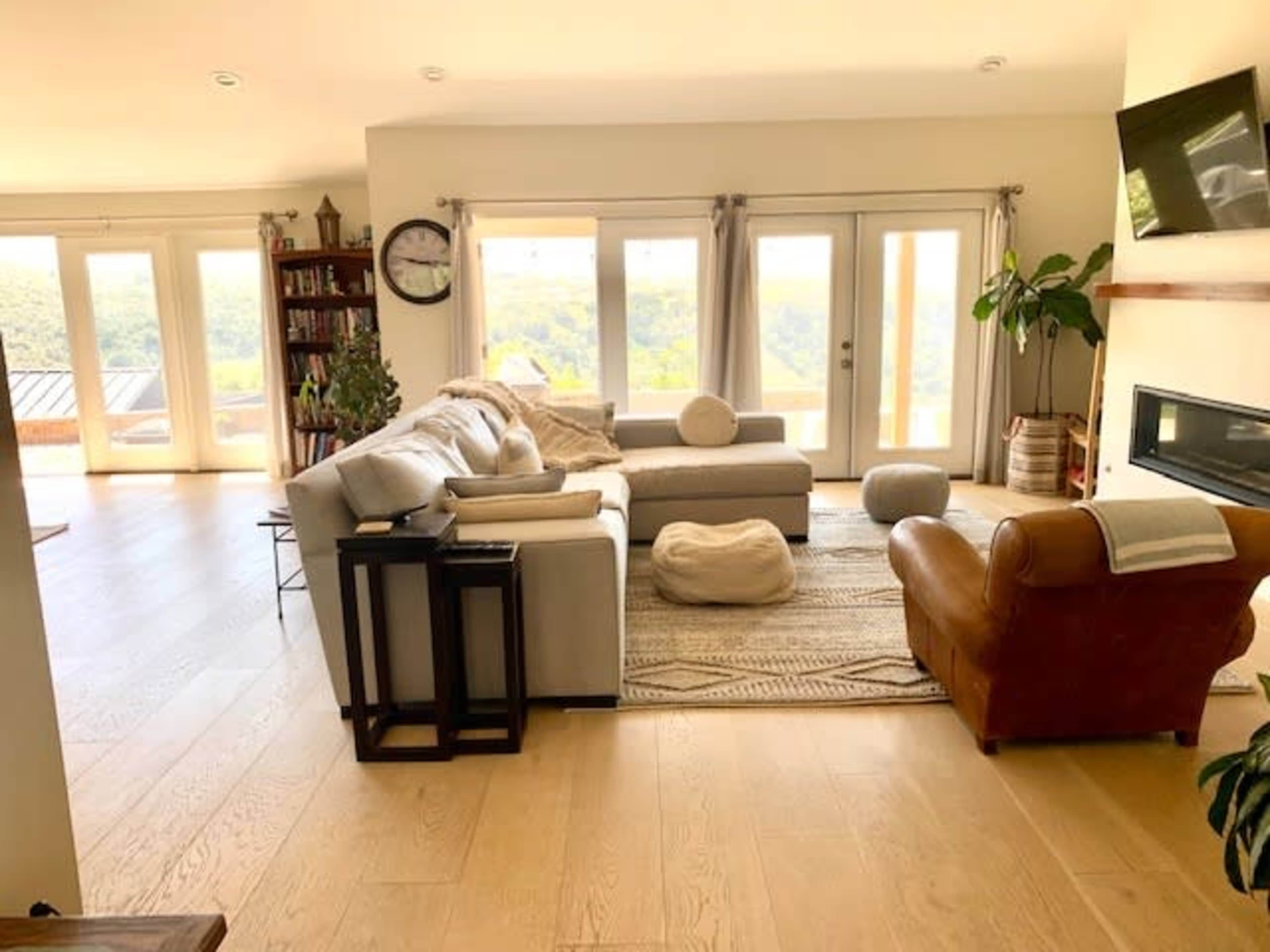 A spacious living room features a sectional sofa, a leather chair, and large windows that overlook a scenic view.