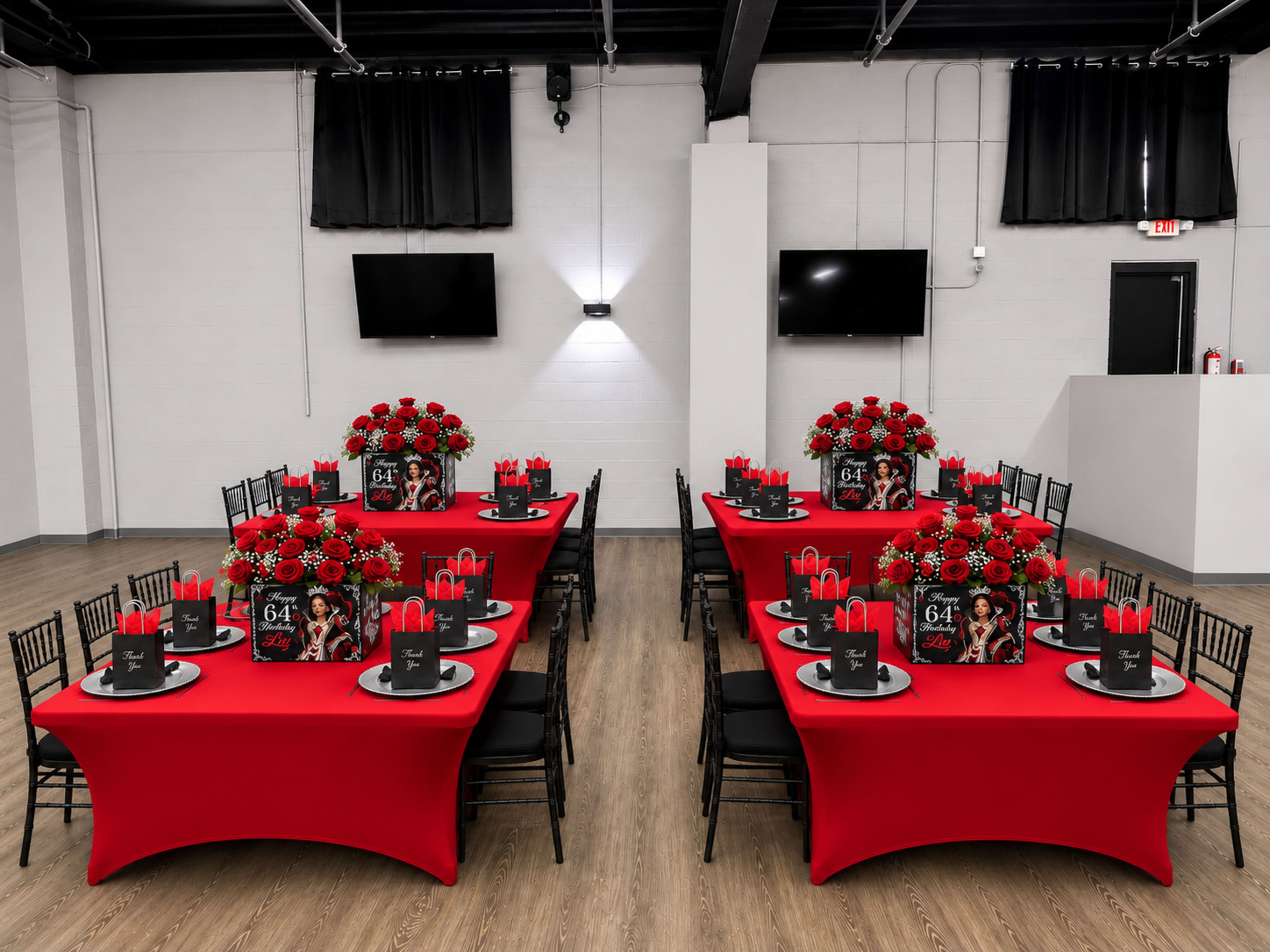 The image shows a banquet hall set up with multiple tables covered in red tablecloths, each adorned with centerpieces of flowers and decorative items for a celebration.