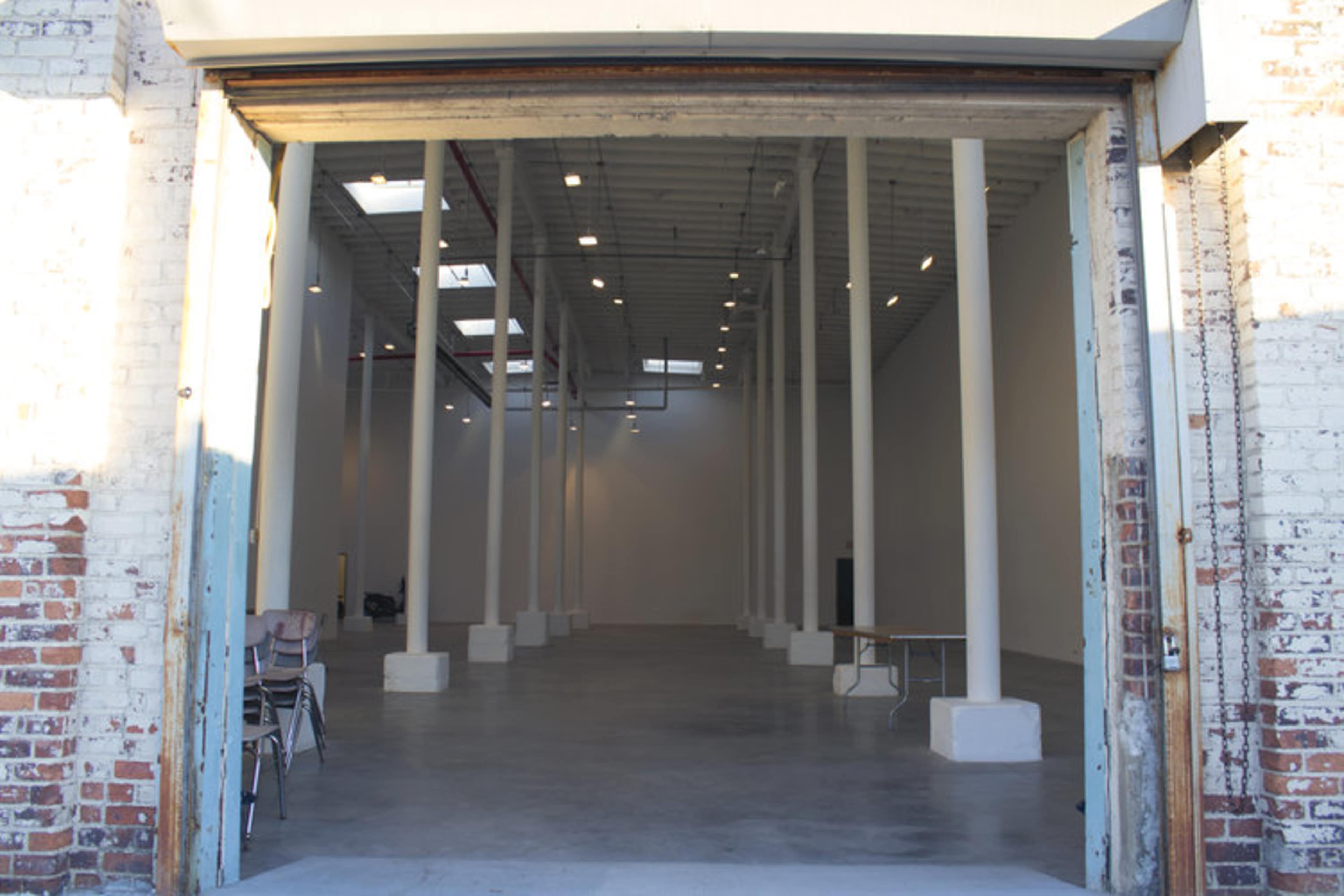 An empty warehouse space with tall columns, a concrete floor, and an open entrance.