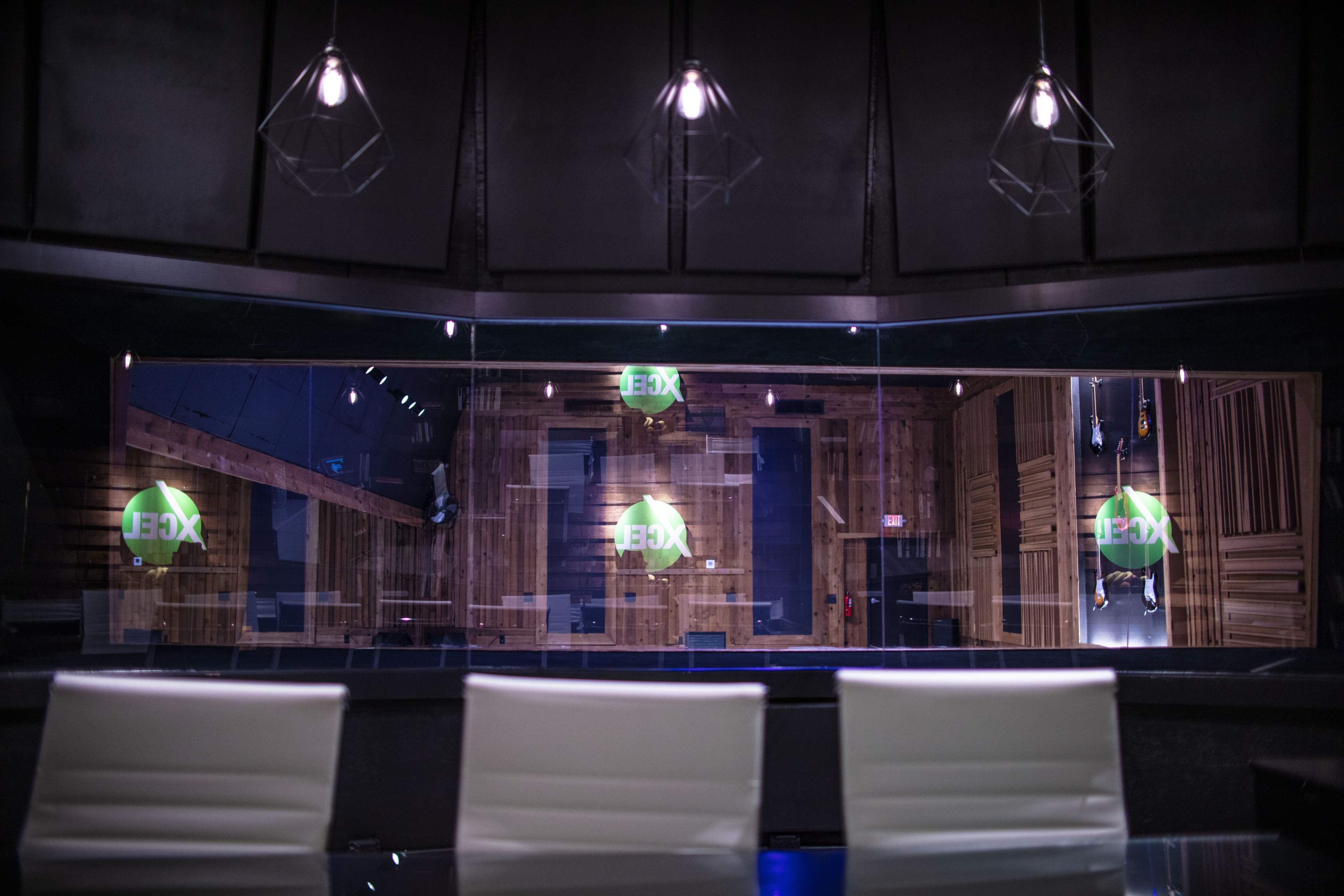 A modern conference room with a large glass wall revealing a wooden interior space illuminated by green and white spherical lights.