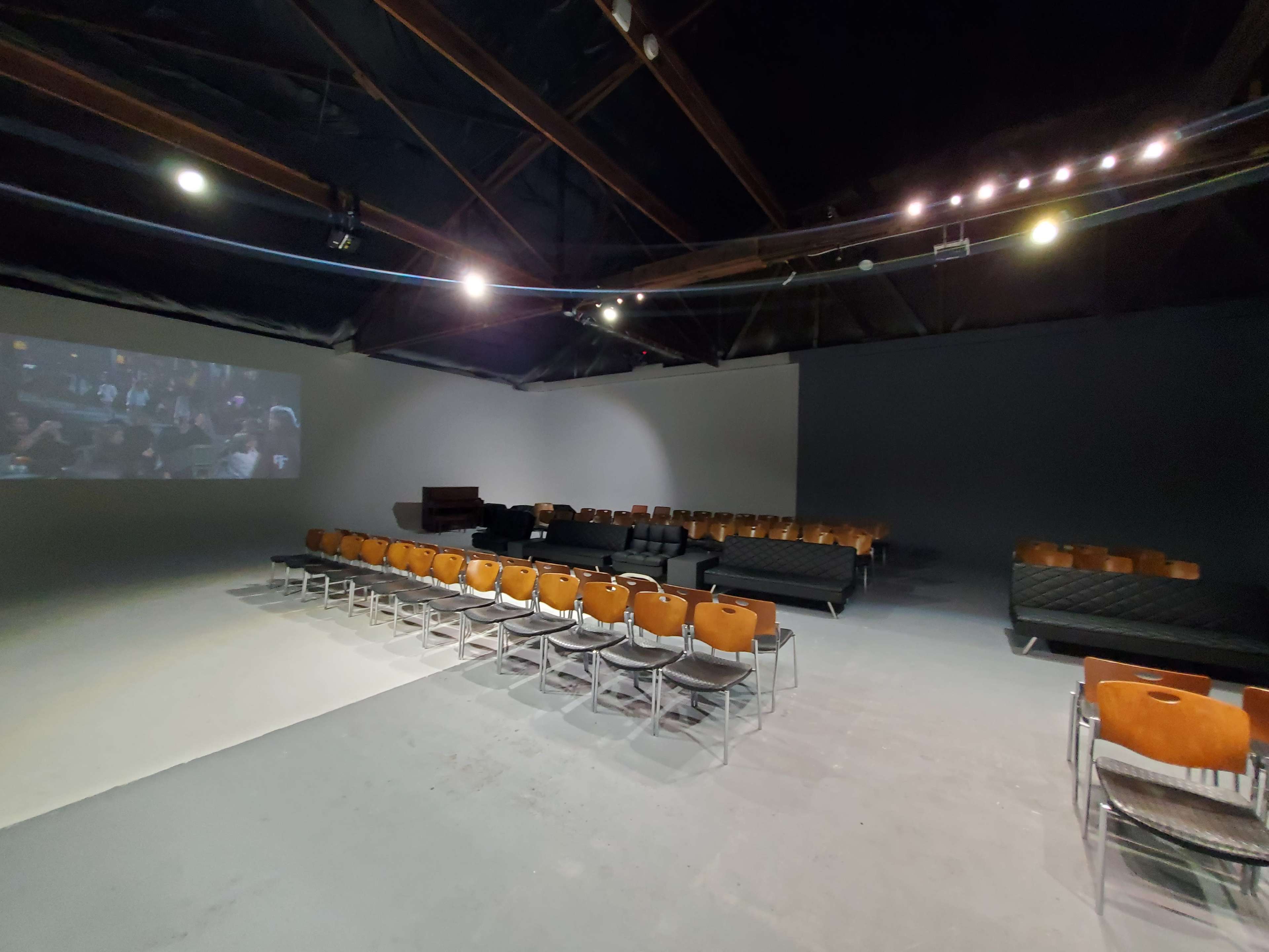 A spacious, empty room arranged with rows of chairs facing a projection screen on one wall.