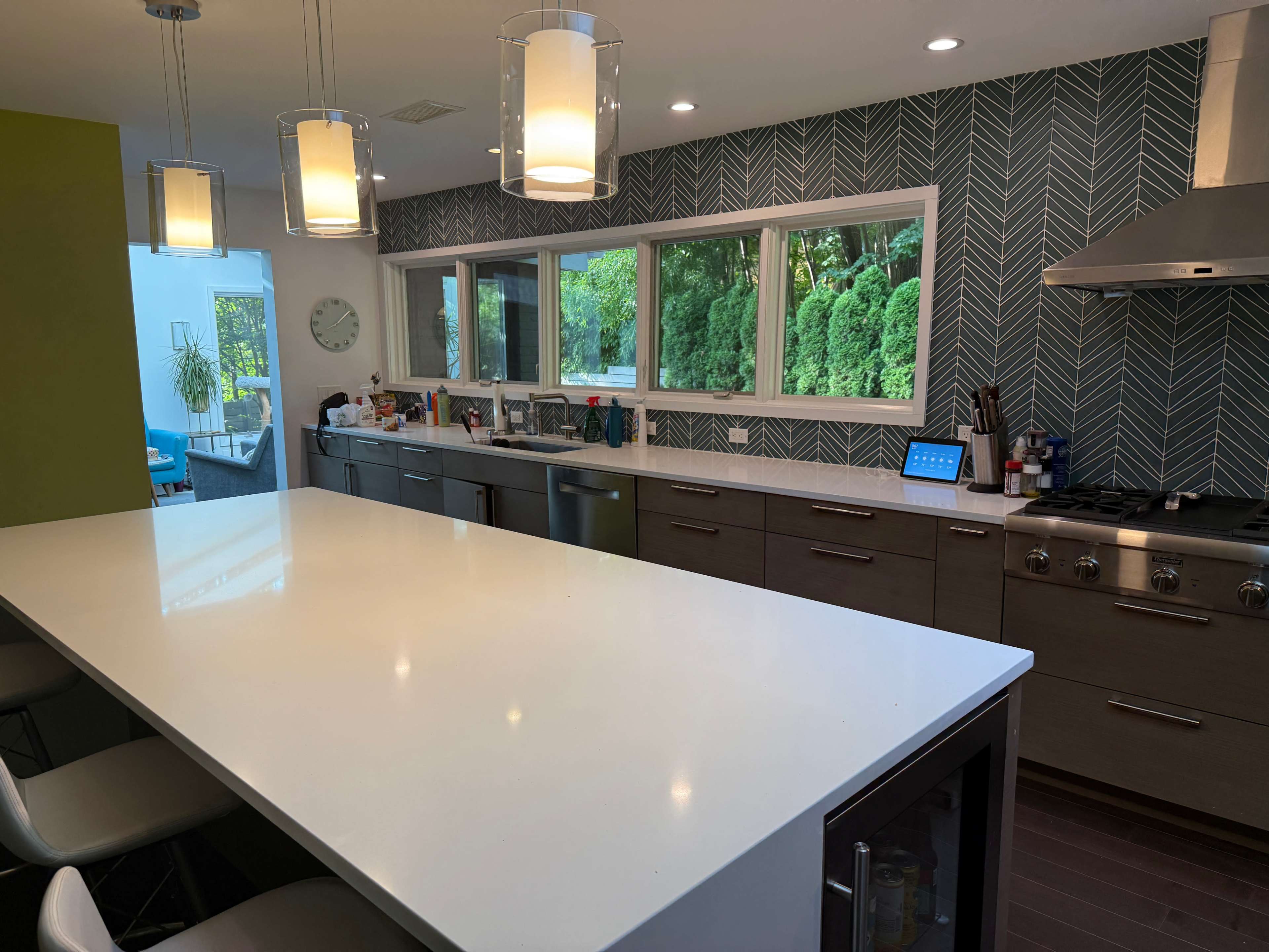 The image shows a modern kitchen with a large white island, stainless steel appliances, and a patterned backsplash.