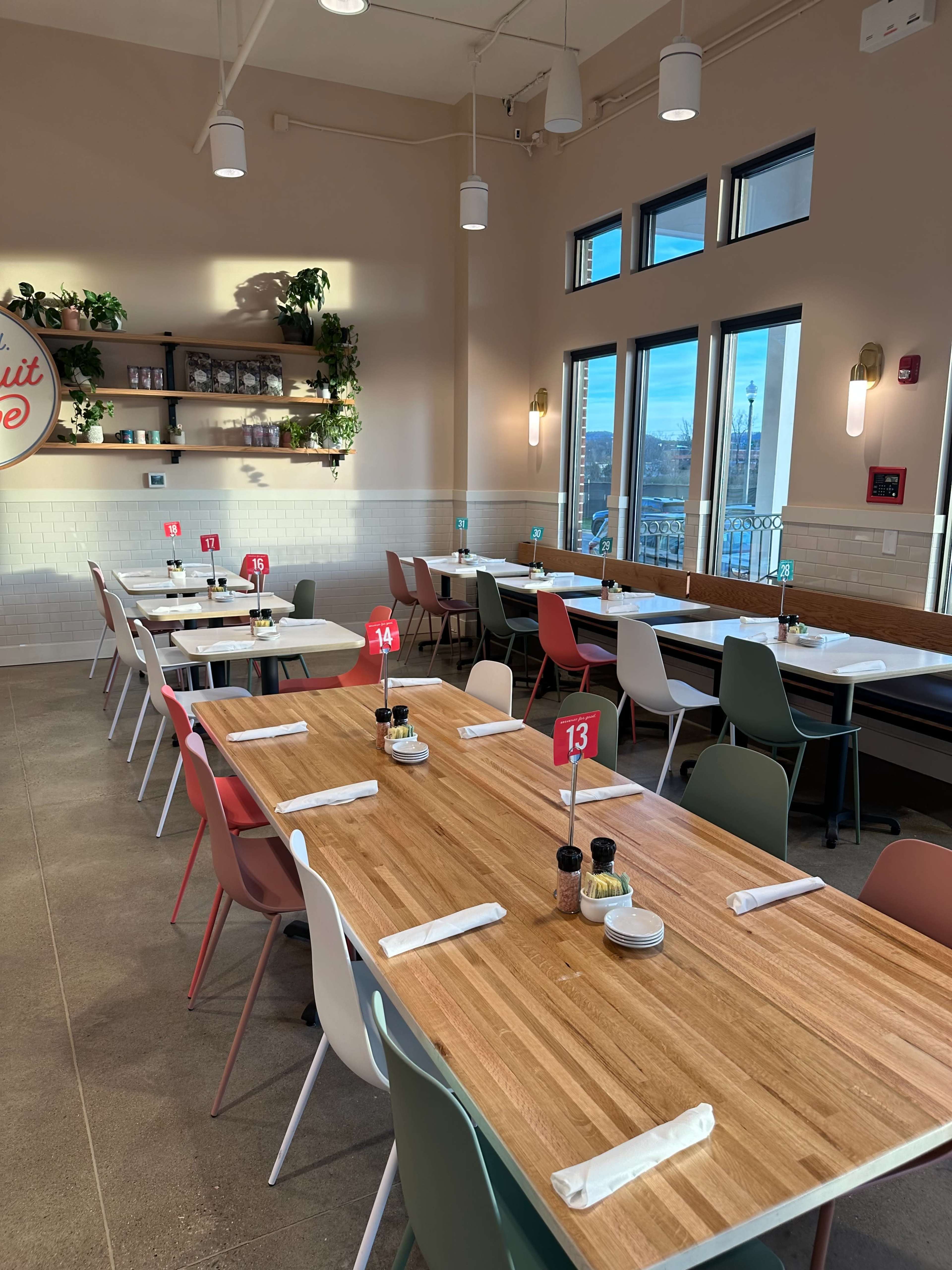 The image shows a brightly lit restaurant interior with multiple tables, each set with numbered stands and condiments.