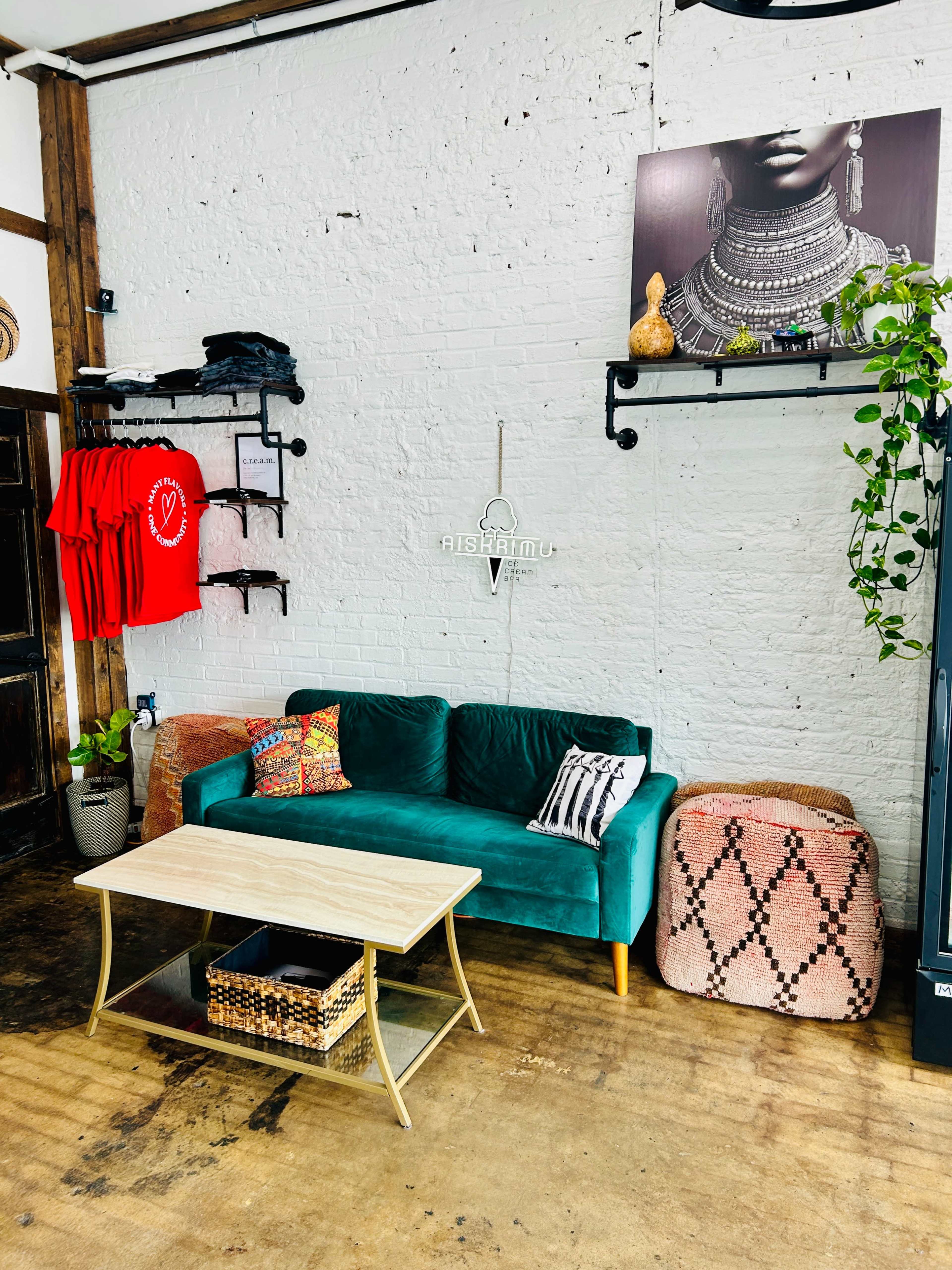 The image shows a cozy interior space featuring a green sofa, a coffee table, and decorative items on shelves against a white brick wall.