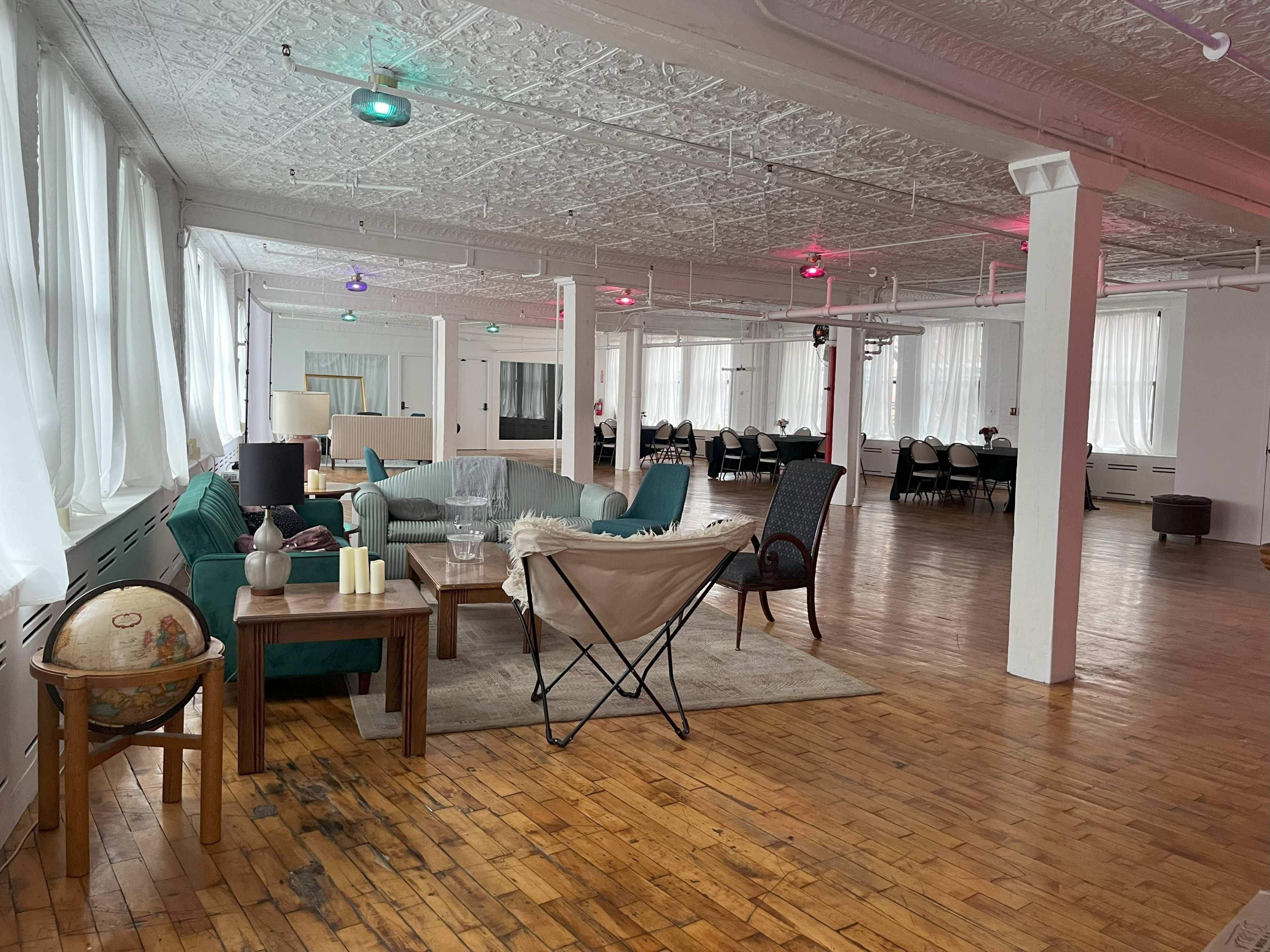 A spacious, modern interior features a seating area with a green couch and a wooden table, illuminated by soft overhead lights.
