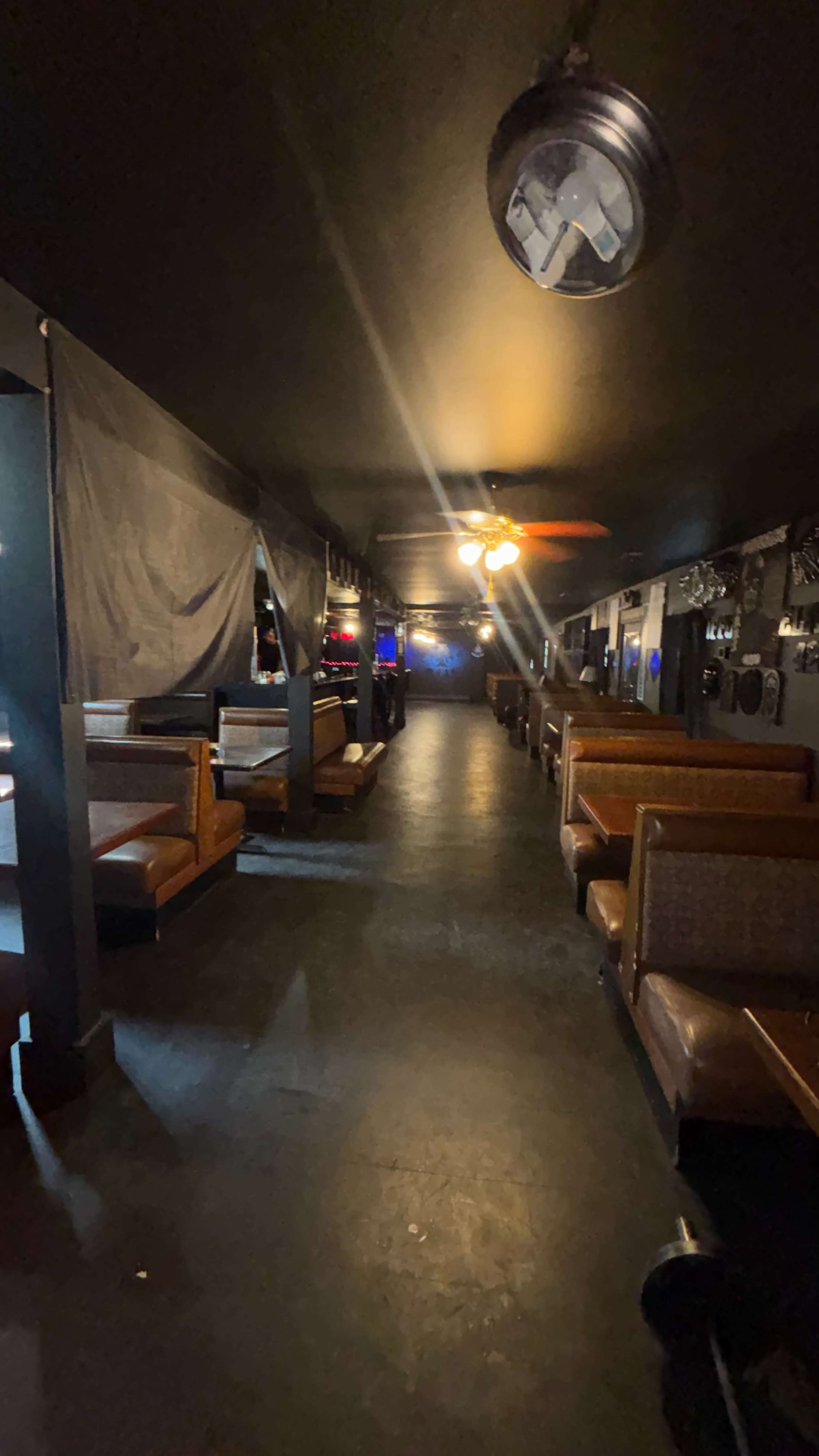 The image shows the interior of a bar or restaurant with booth seating along a dimly lit corridor.