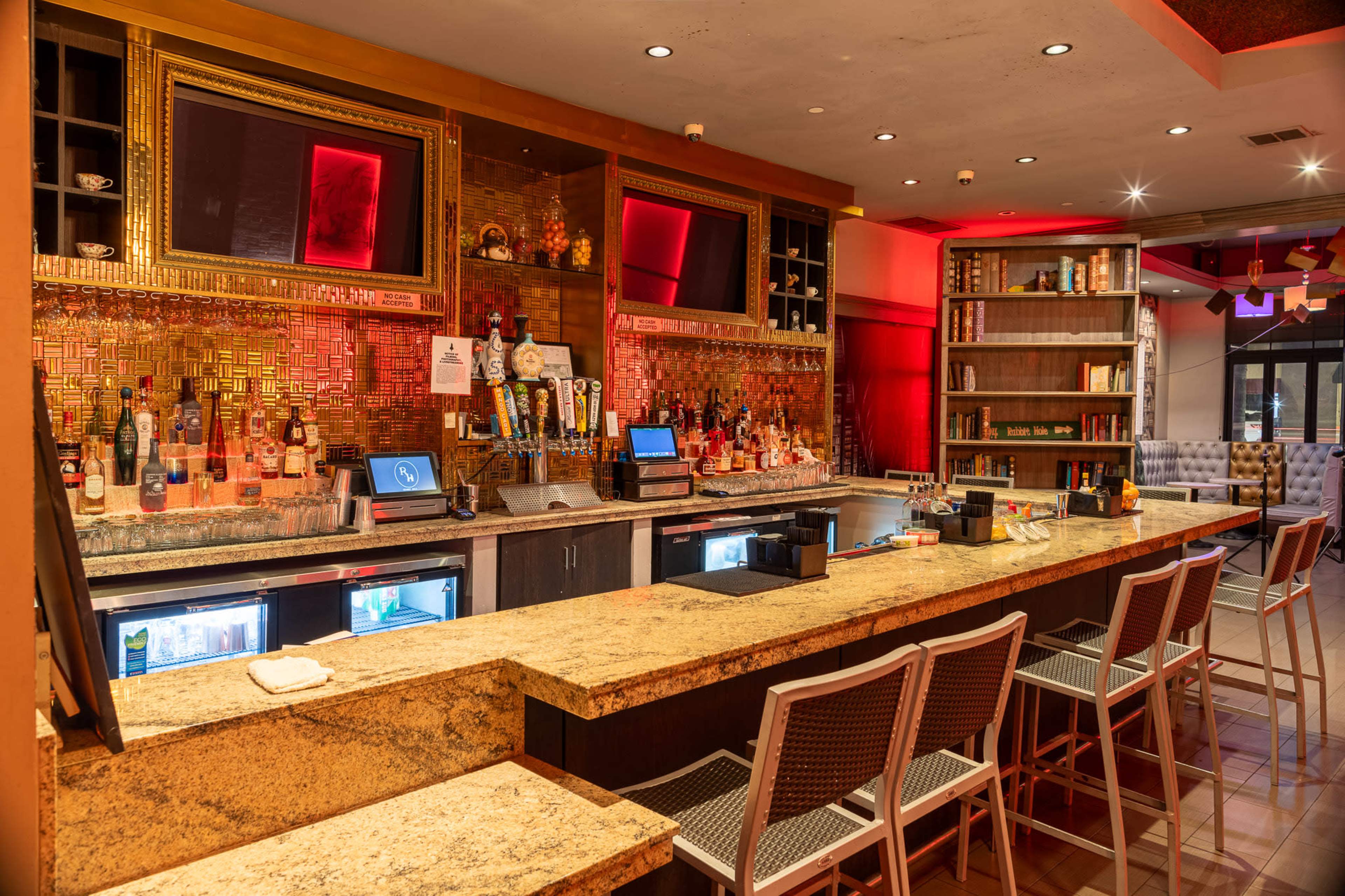 A well-designed bar area with a granite countertop, shelves stacked with bottles, and several high-backed chairs arranged in front.