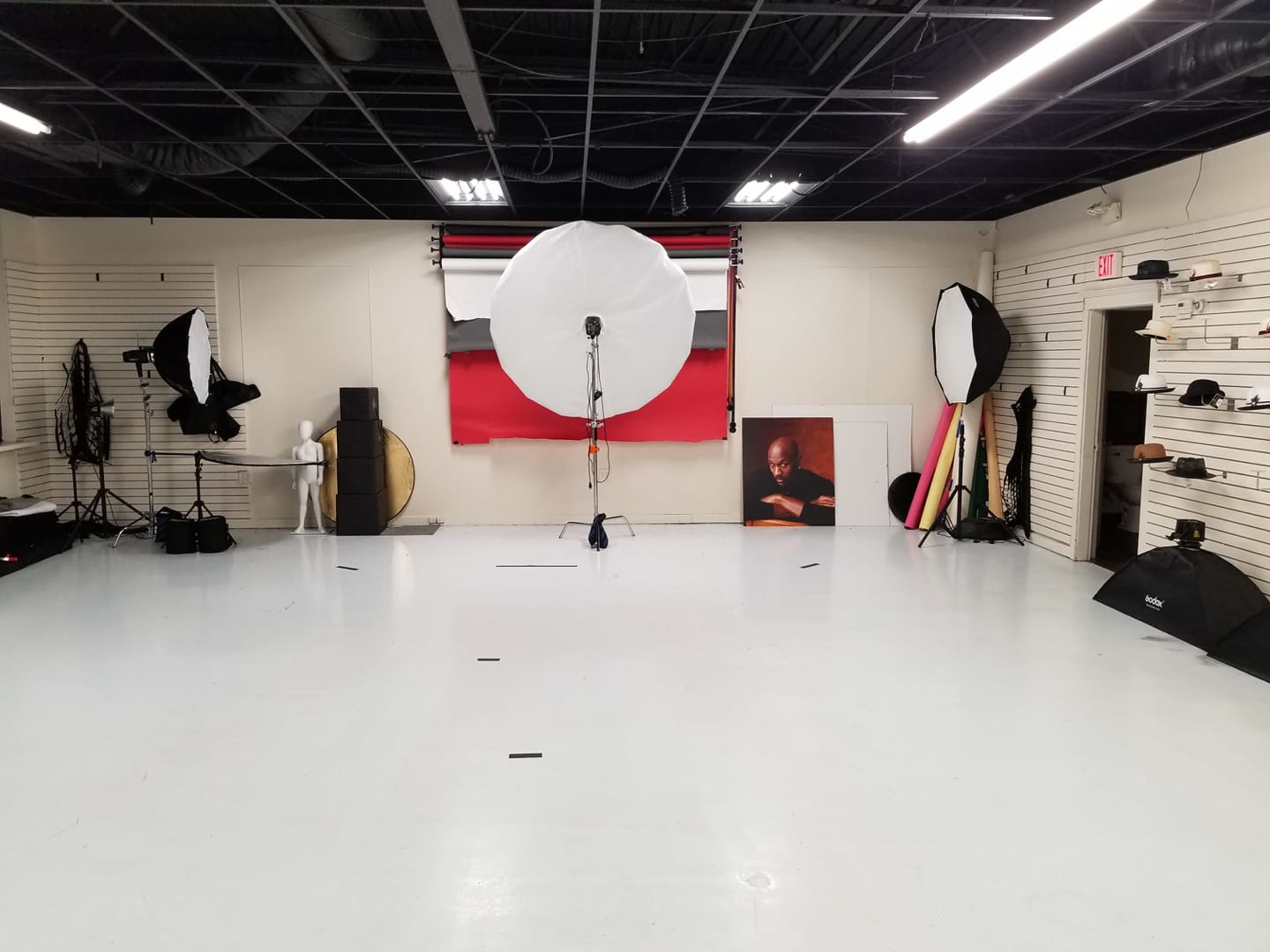 A photography studio with various lighting equipment, backdrops, and props arranged in a spacious, well-lit area.