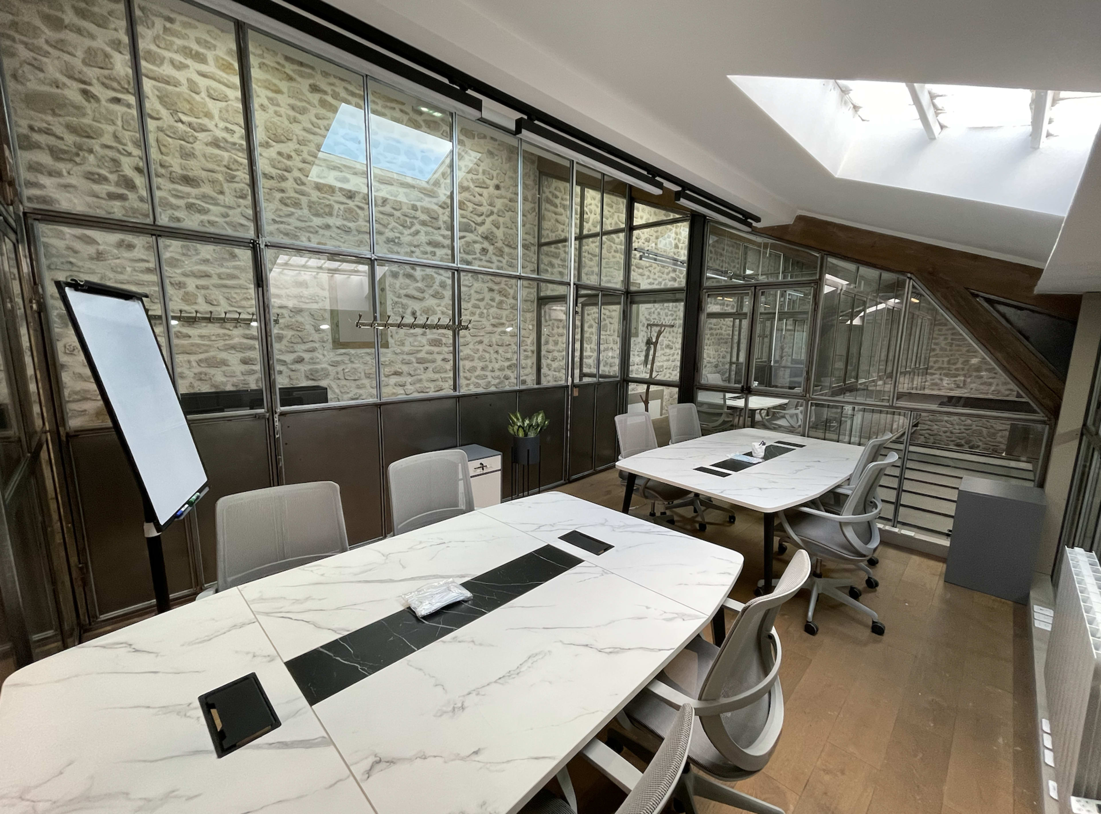 A modern conference room features a long marble table, sleek chairs, and glass walls showcasing a stone interior.