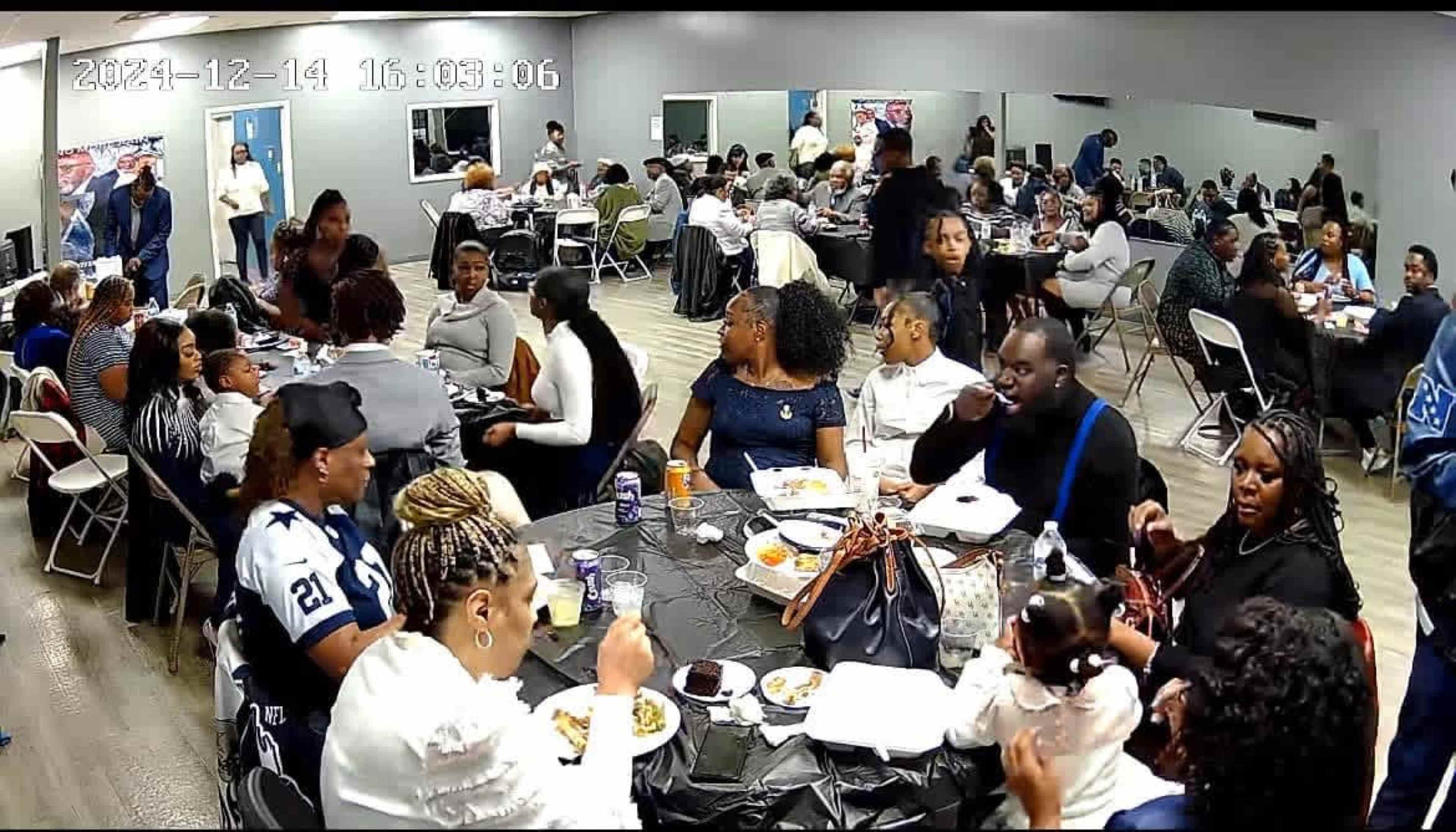 A large group of people gathers around several tables in a banquet hall, enjoying a meal and engaging in conversation.