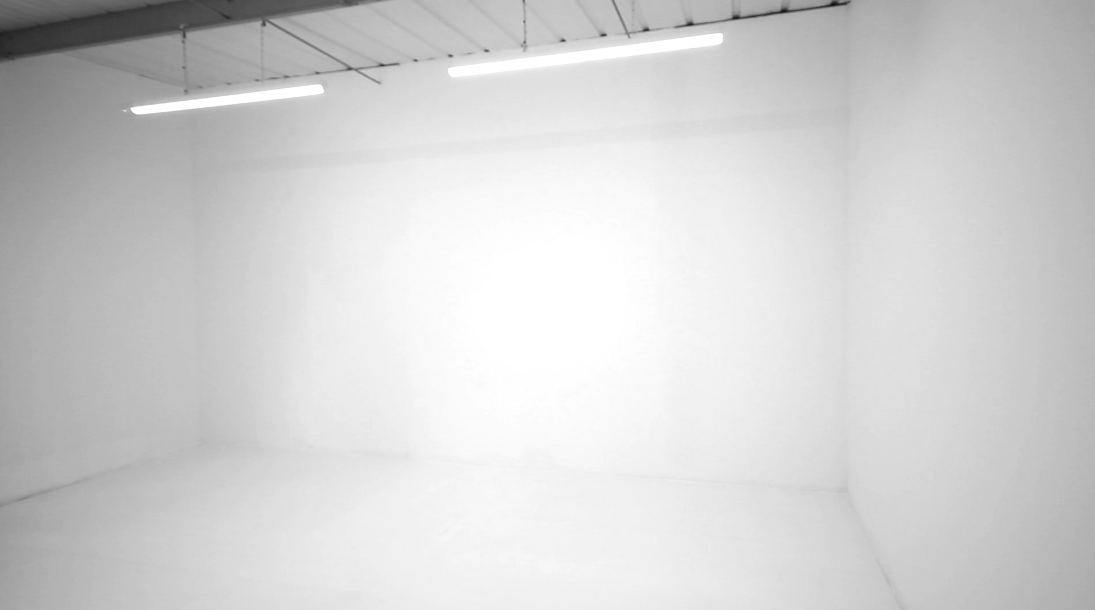 The image shows a plain, empty white room with two overhead lights illuminating the space.