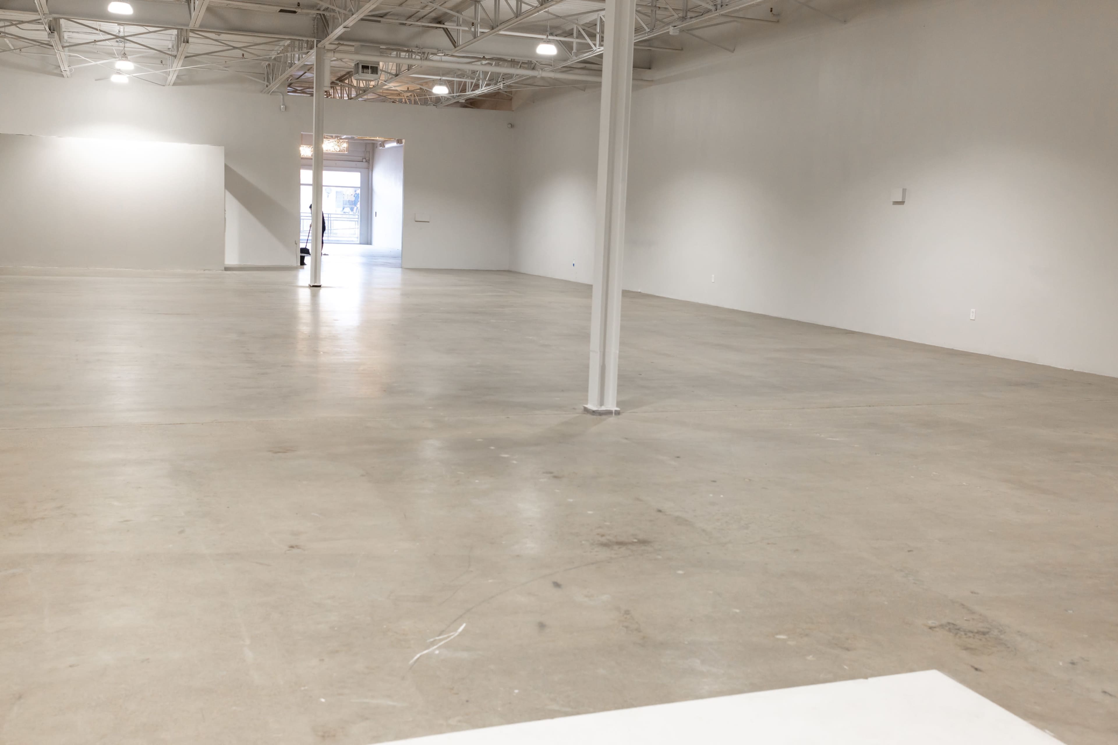 An empty, industrial-looking interior space with gray concrete flooring and white walls.