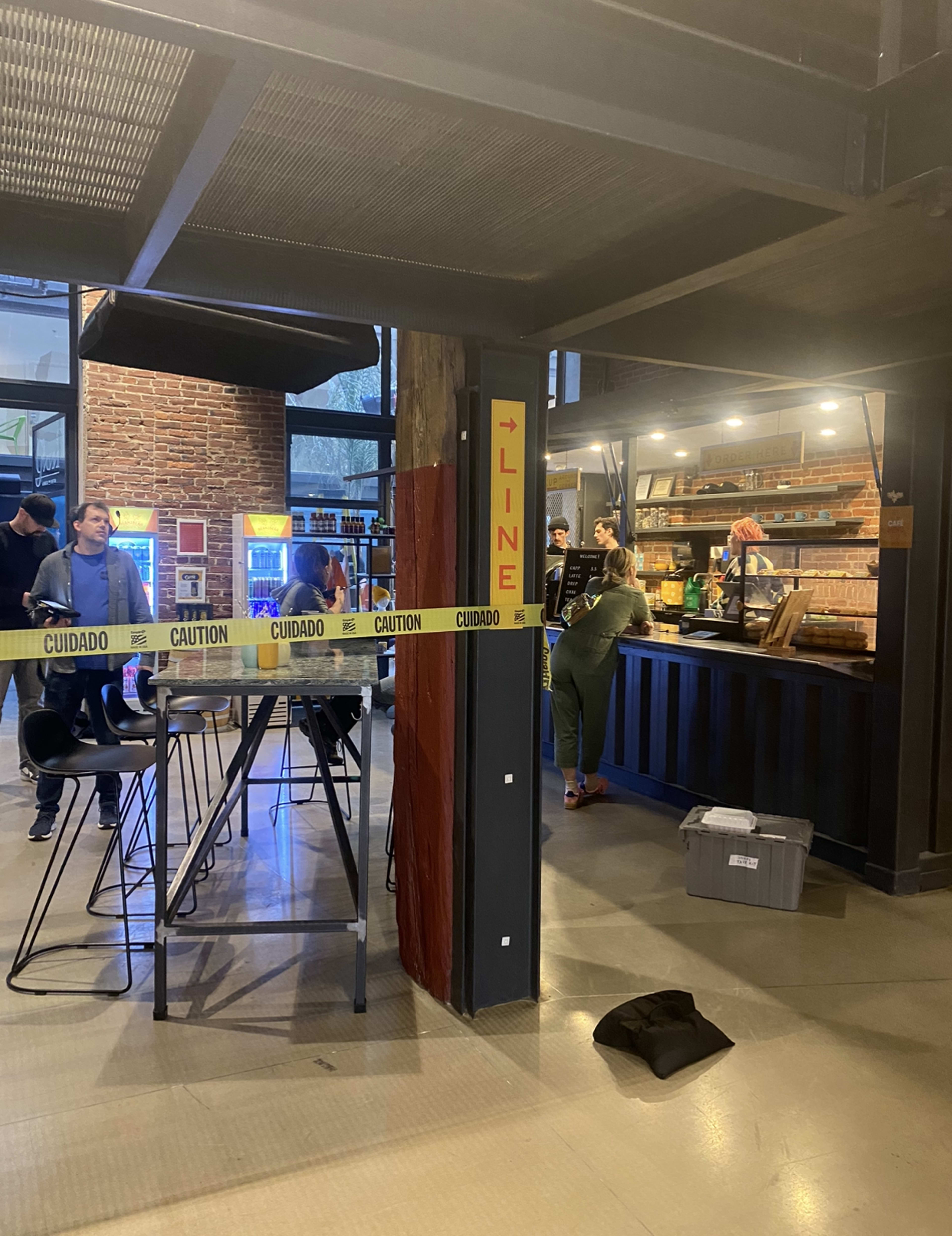 A bustling café scene features customers ordering at the counter, with a "LINE" sign and caution tape indicating the queue area.