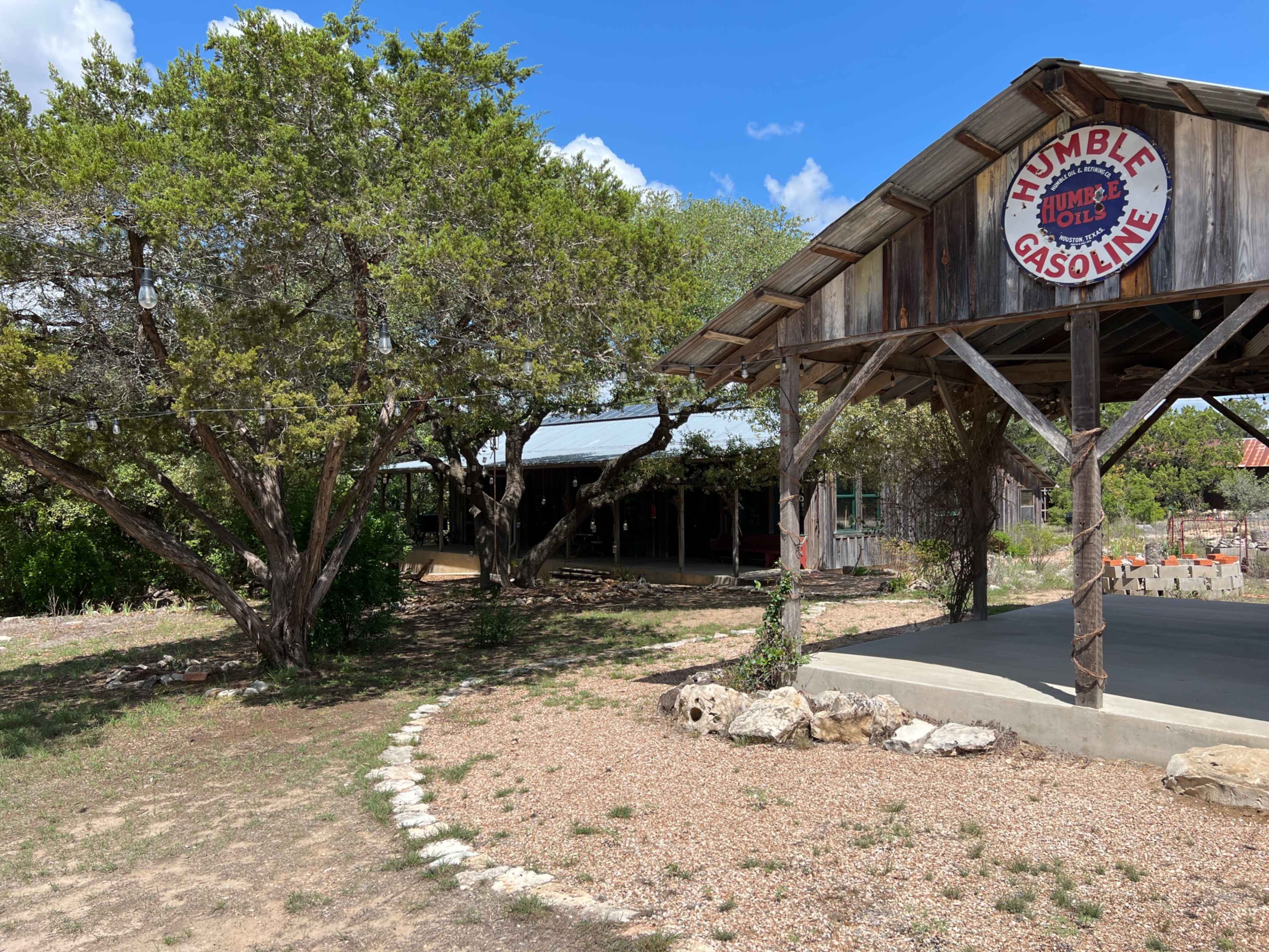 The scene features an old gas station with a "Humble Gasoline" sign, surrounded by trees and rocky landscaping.