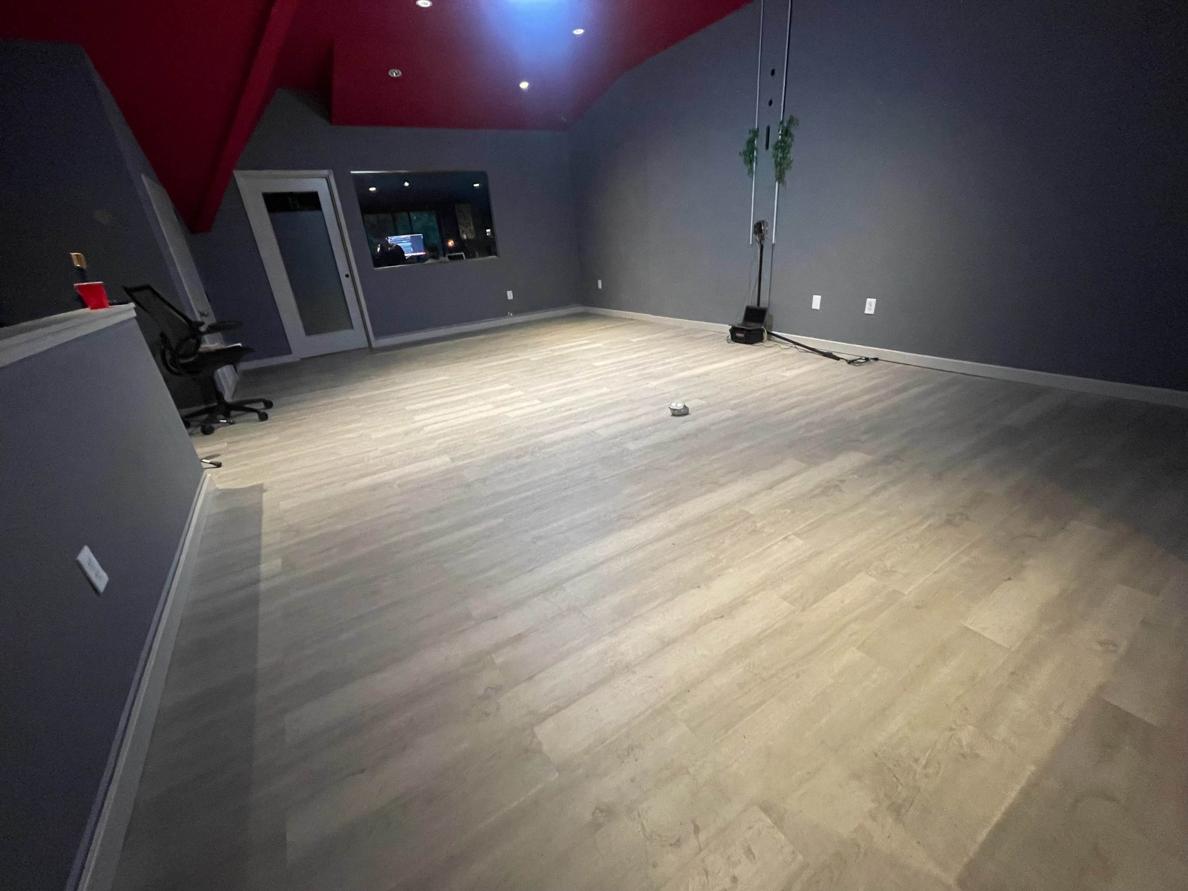 A partially furnished room with gray walls, a red ceiling, and wooden flooring.
