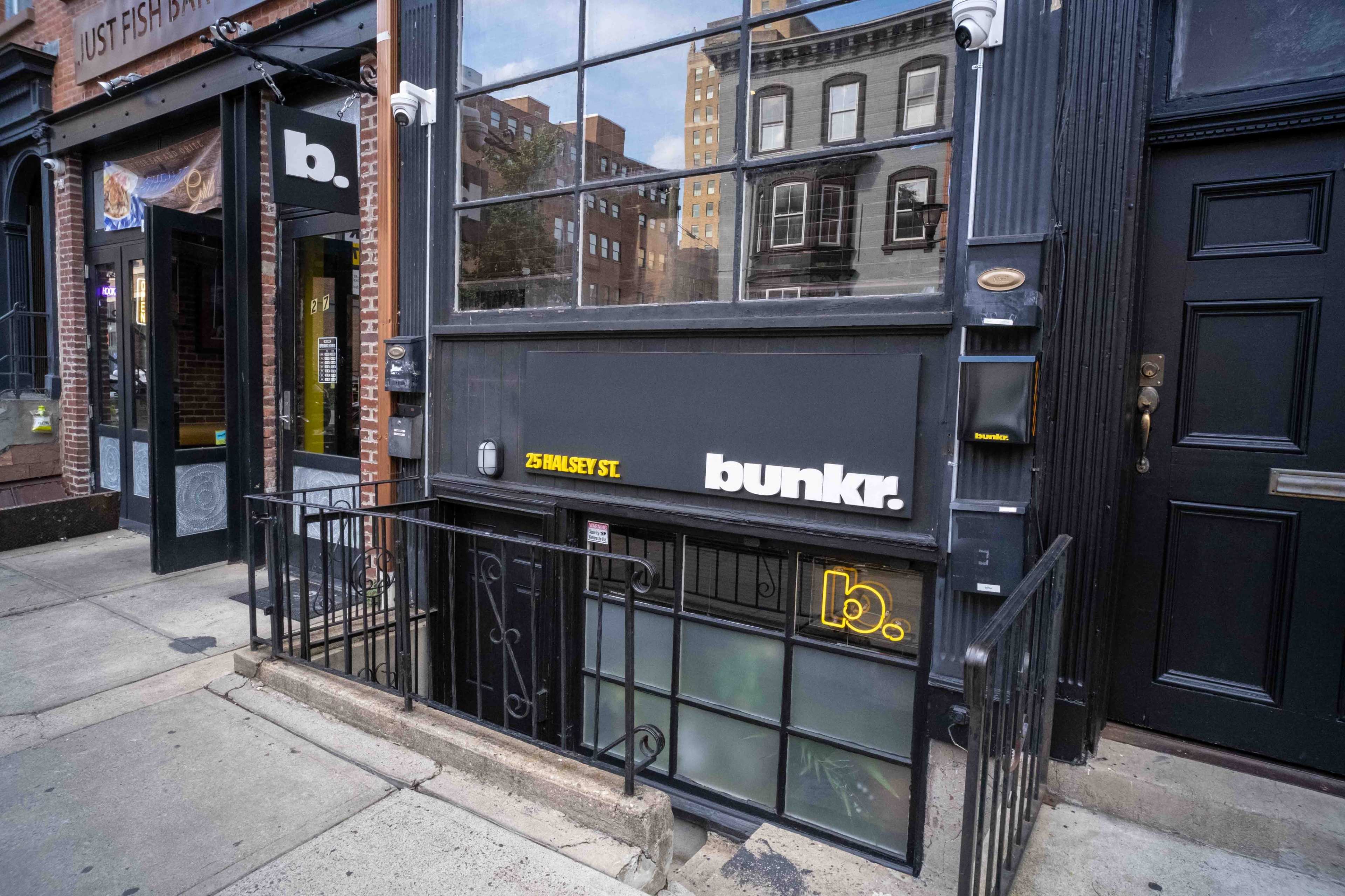 The entrance to a place called "bunkr." located on a street with buildings in the background.