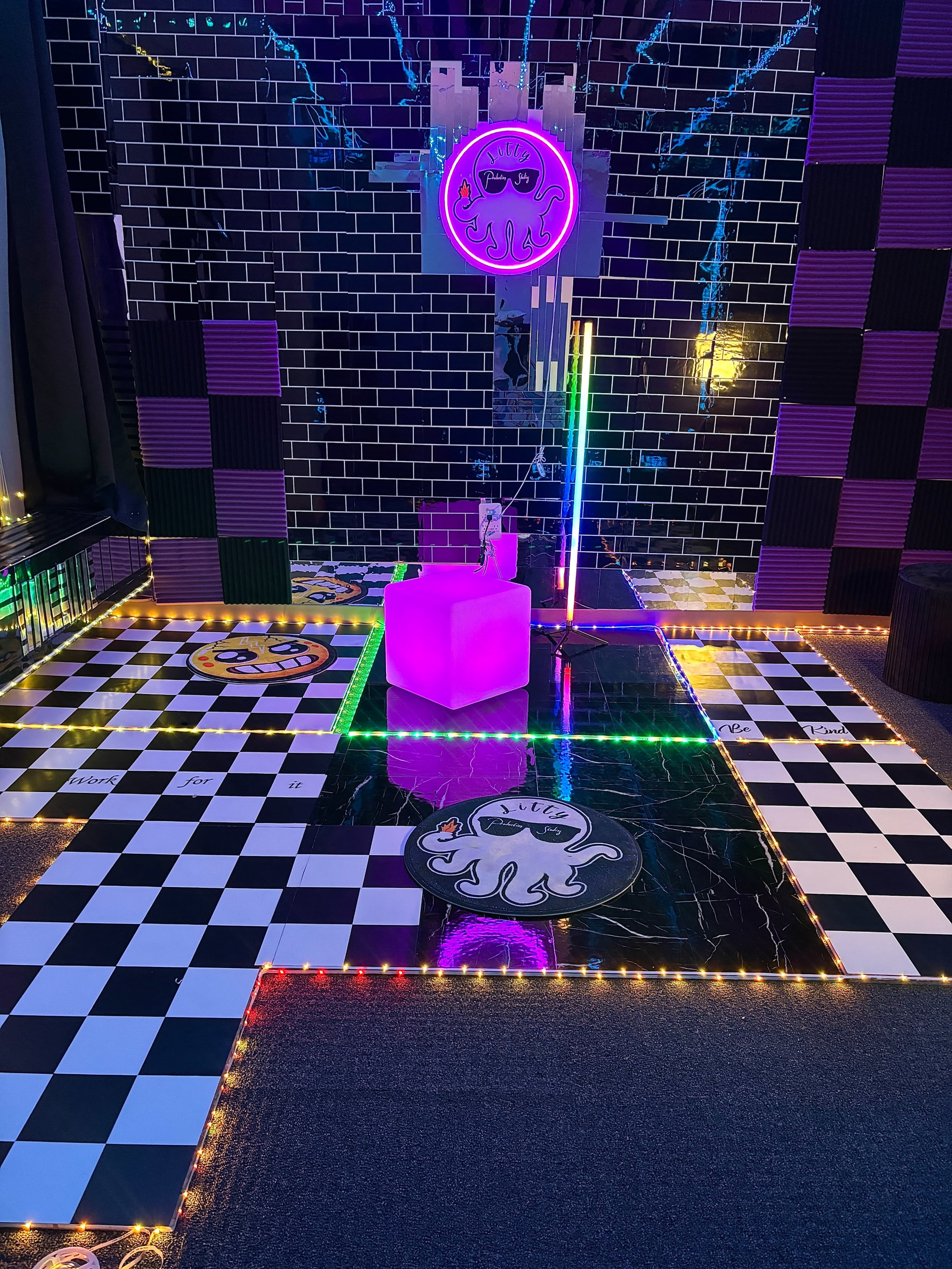 The image depicts a brightly lit room with a checkered floor, neon lights, and colorful decorations featuring an octopus design.