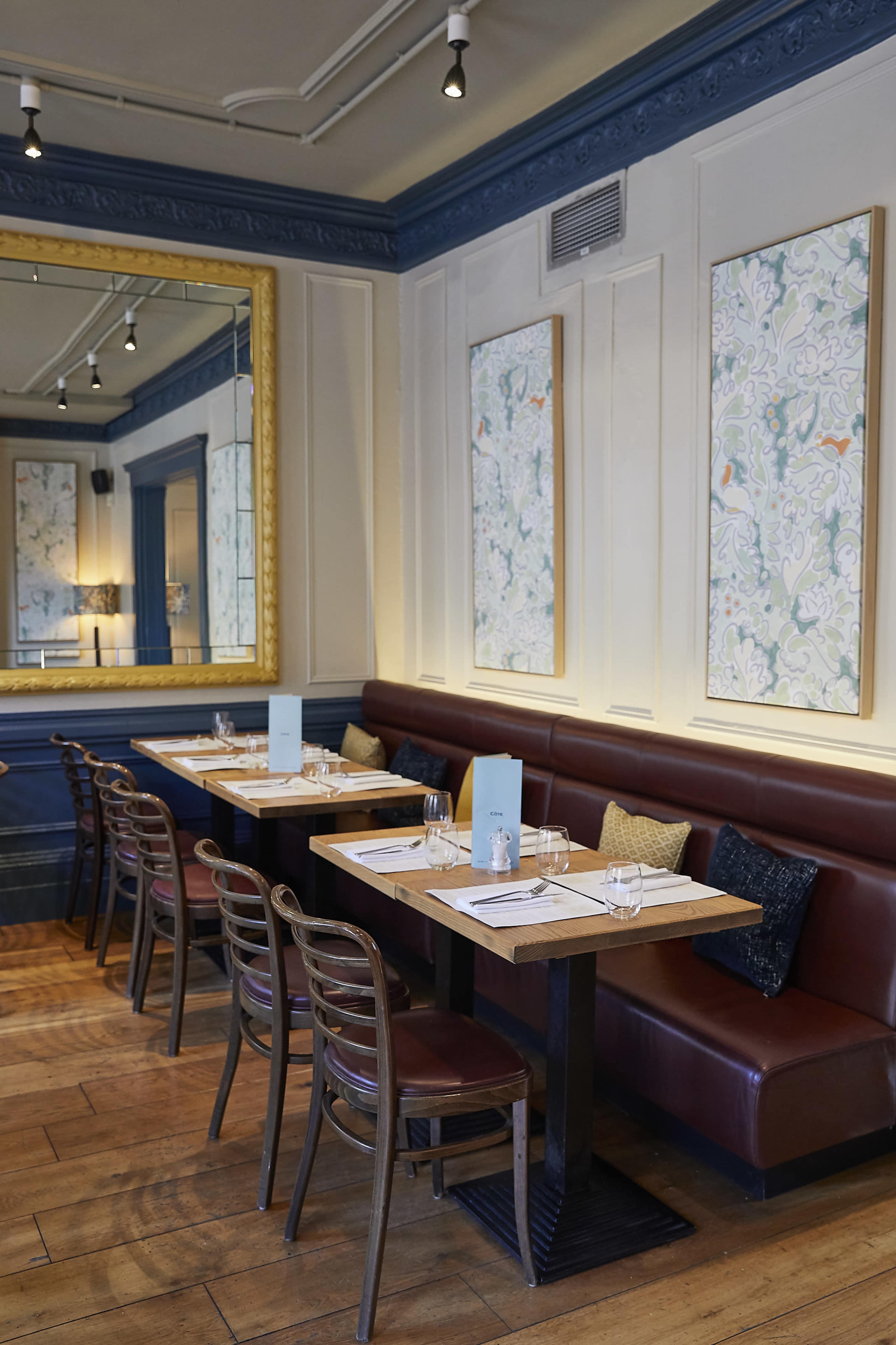 The image features a restaurant interior with wooden tables, leather seating, and decorative wall art.