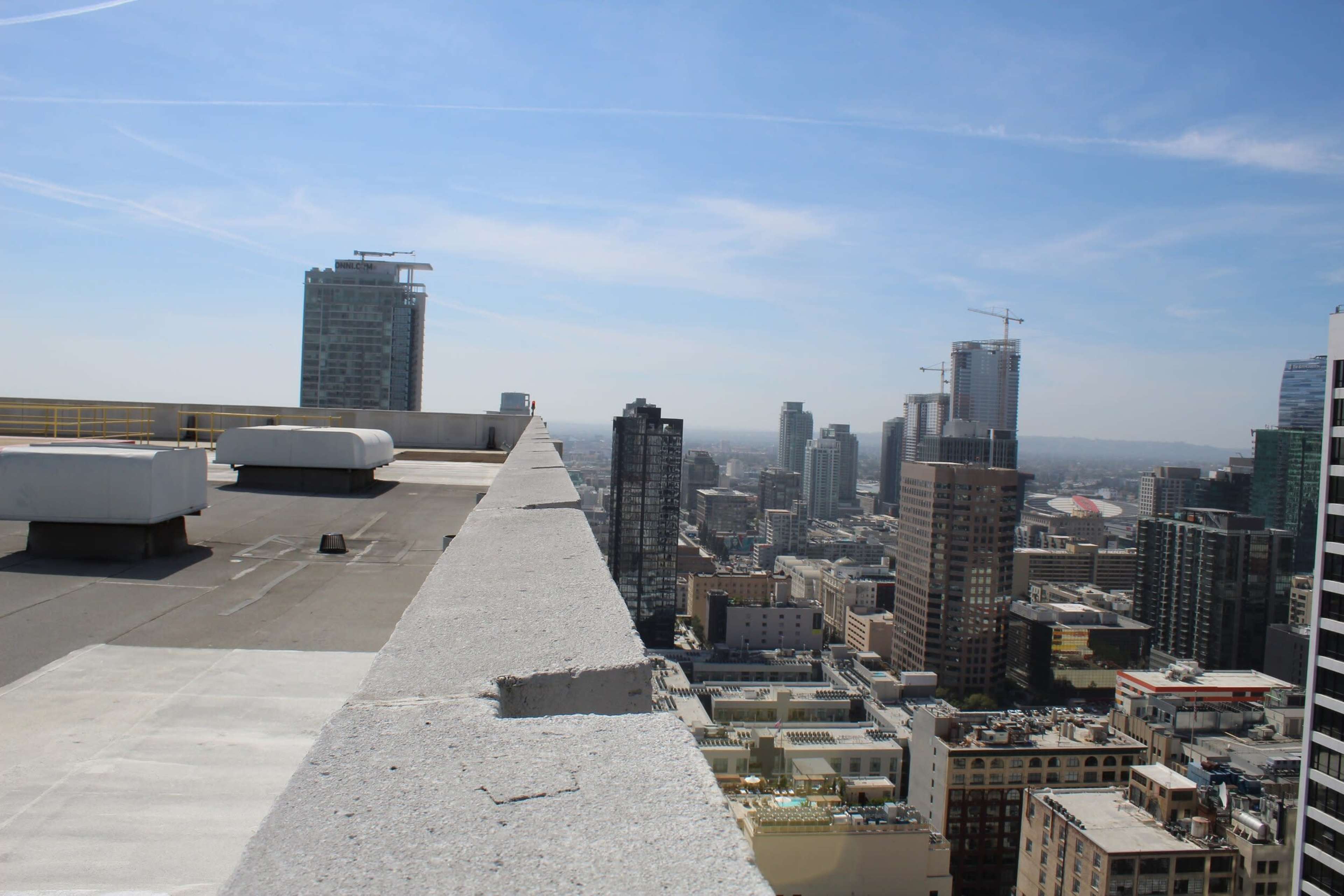 A rooftop view of a city skyline, featuring various high-rise buildings and a clear blue sky.