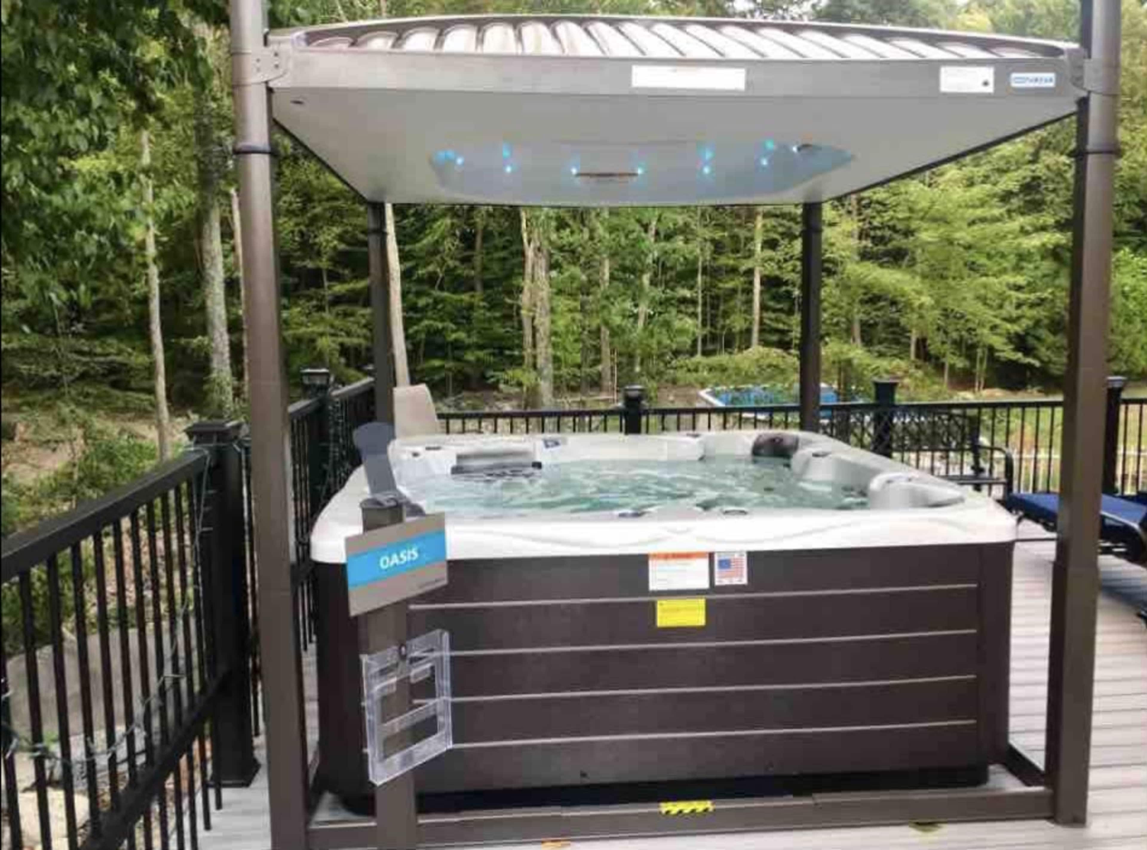 A hot tub under a roof on a deck surrounded by trees.