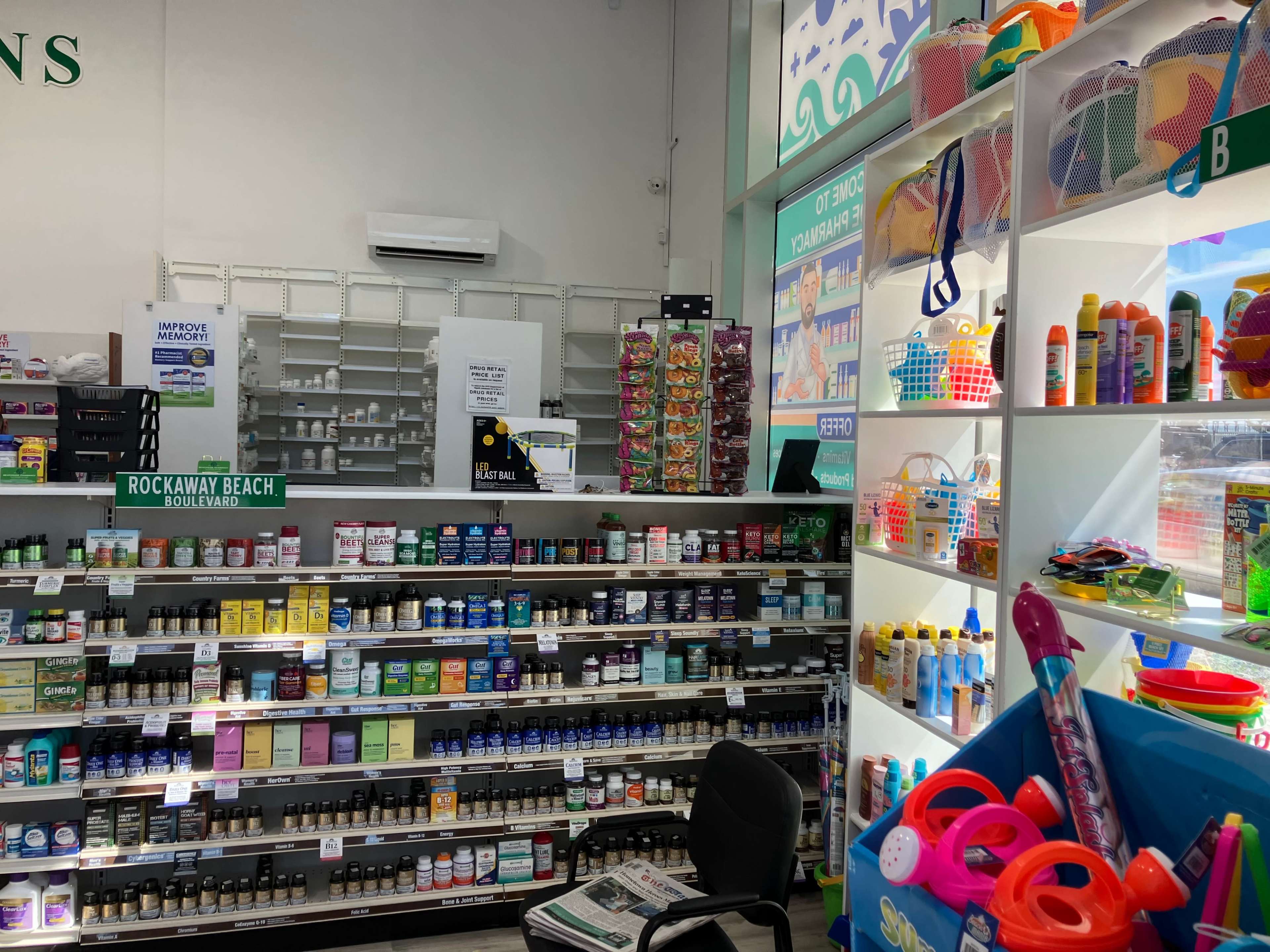 The image shows the interior of a retail store with shelves displaying various health products and a section featuring colorful toys and sunblock items.