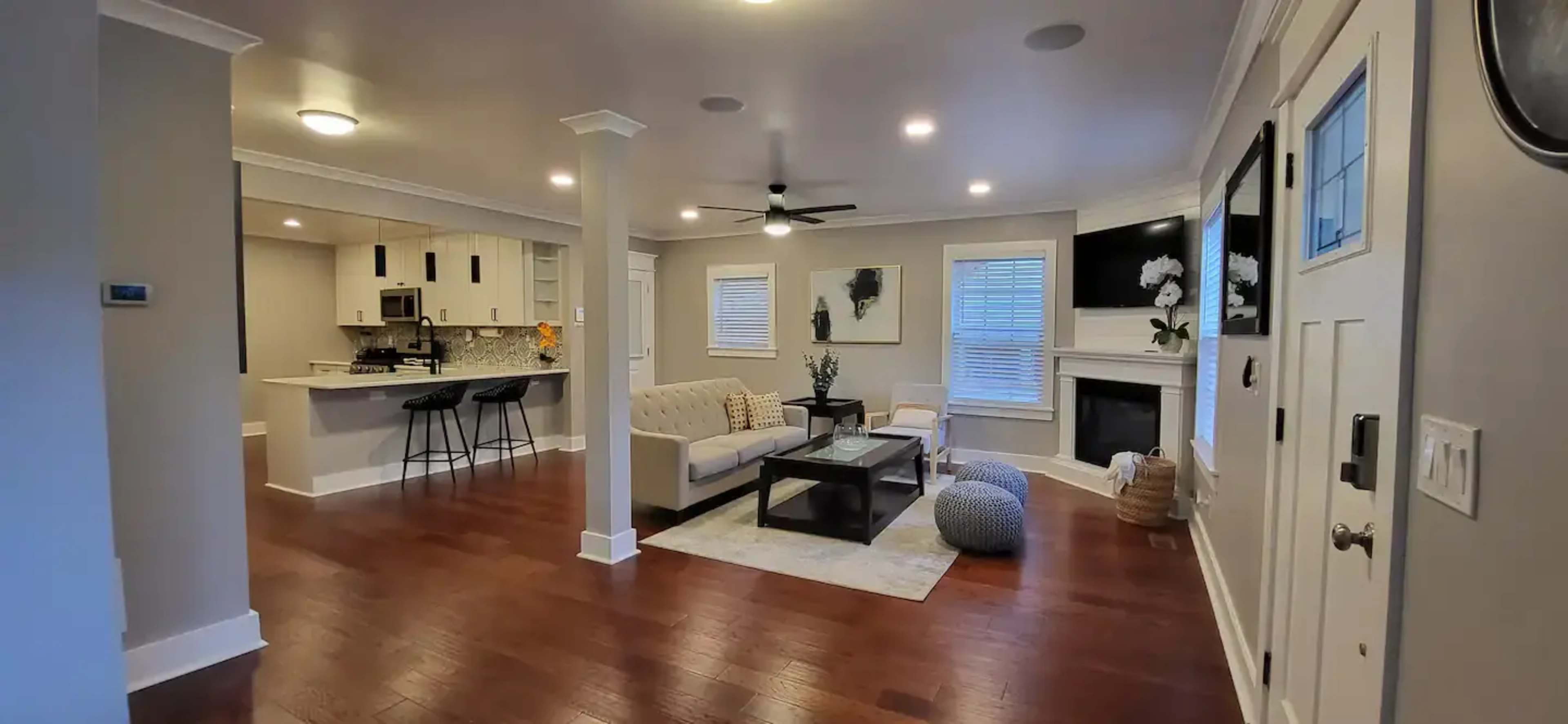 The open-concept living area features a cream-colored sofa, a coffee table, and a kitchen with modern appliances in the background.