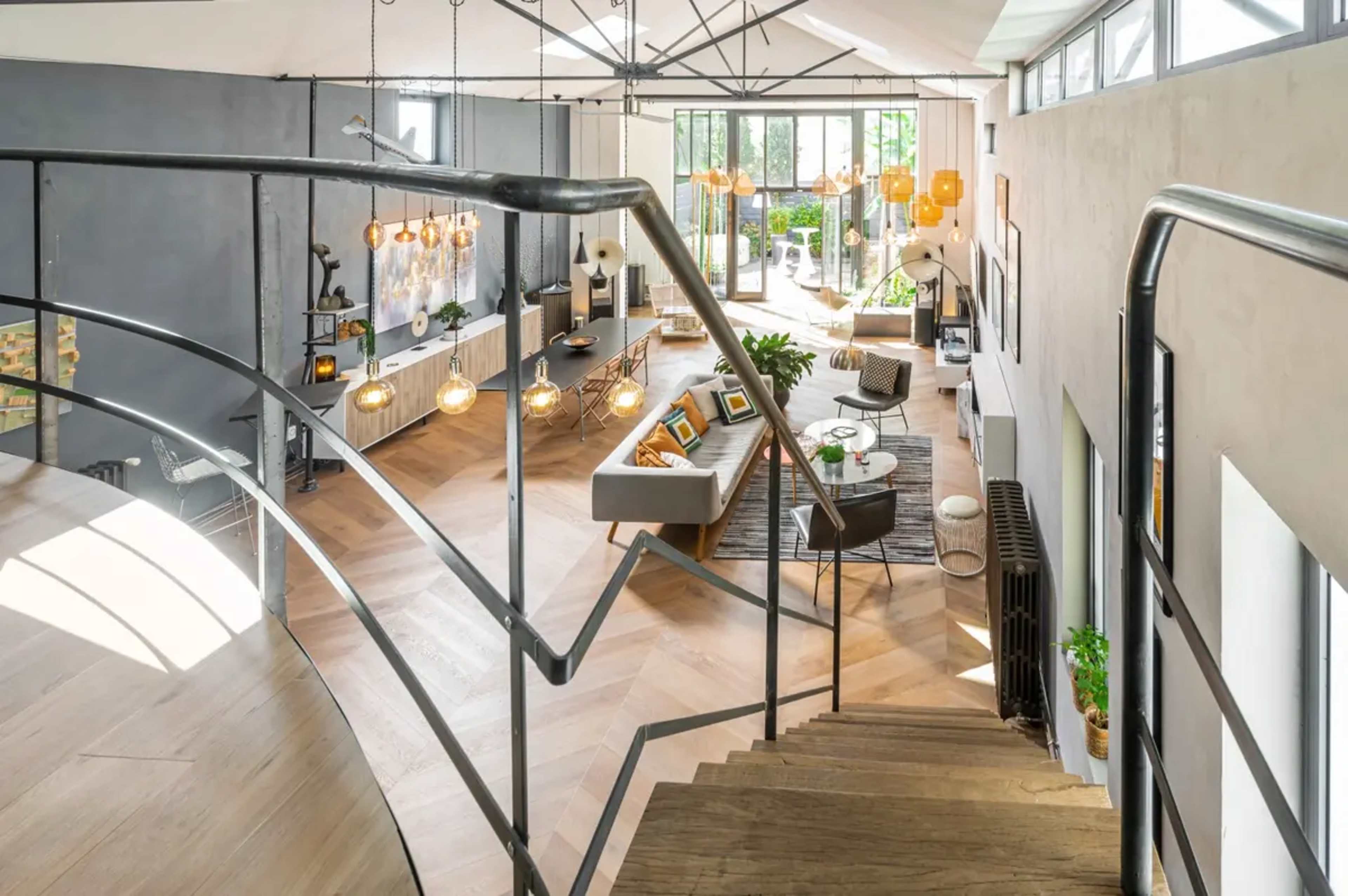A modern, open-concept living space with a winding staircase, large windows, and stylish furnishings.
