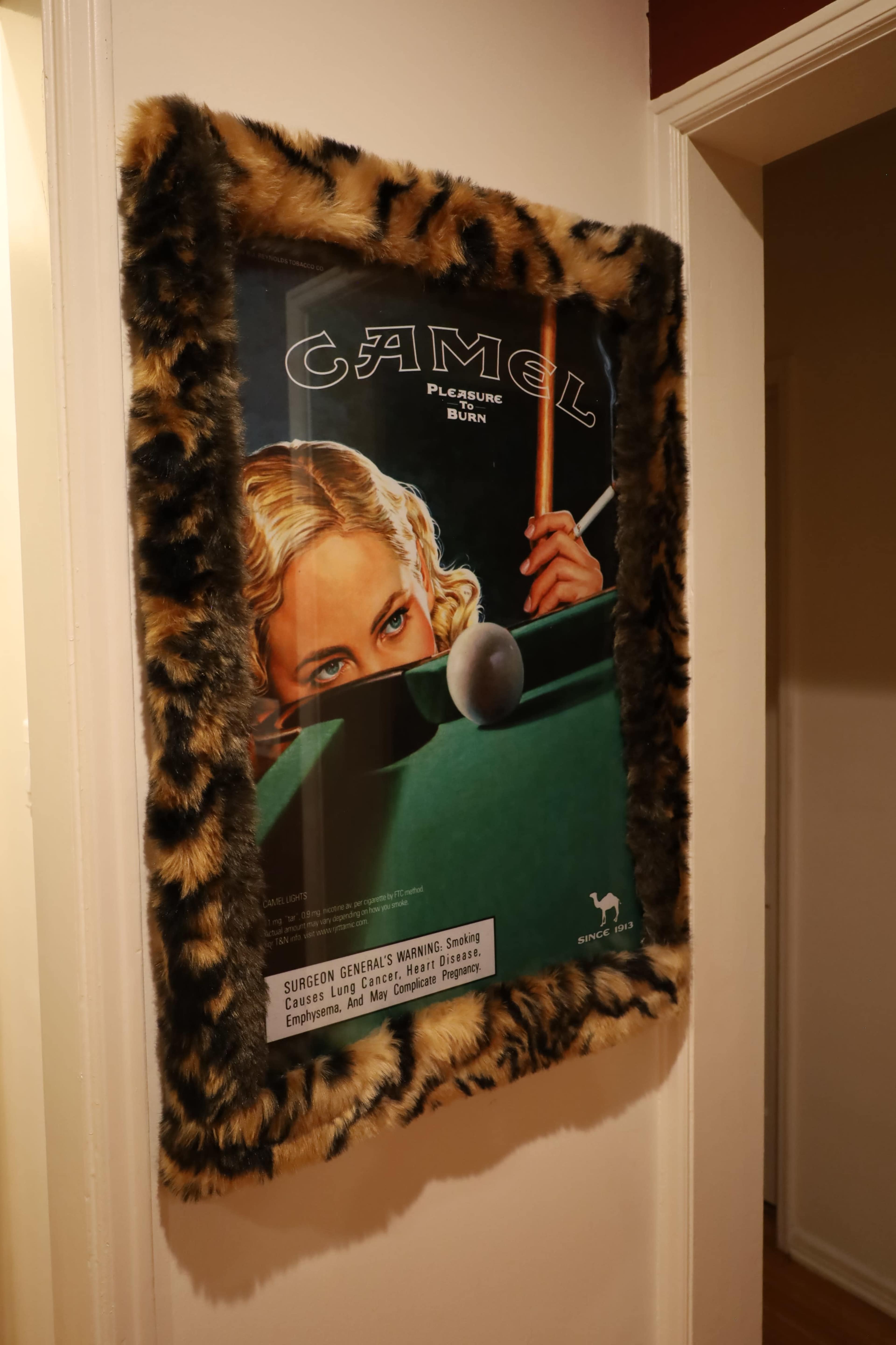 The image shows a framed vintage Camel cigarette advertisement featuring a woman aiming at a billiard ball.